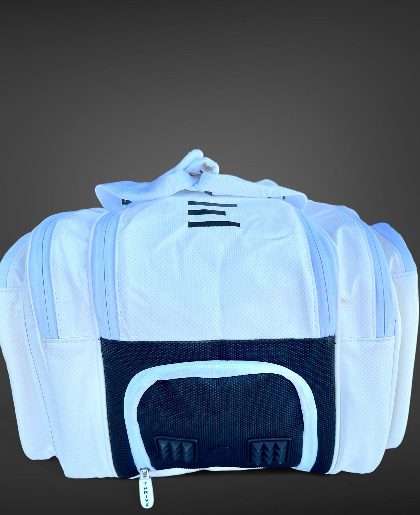 The Thrive Pickleball Elite Pro Tour Bag w/shoe bag in white features vegan leather, black accents, side and front zippered pockets, a mesh panel, sturdy handles, and a logo-branded zipper pull on a gray gradient background.