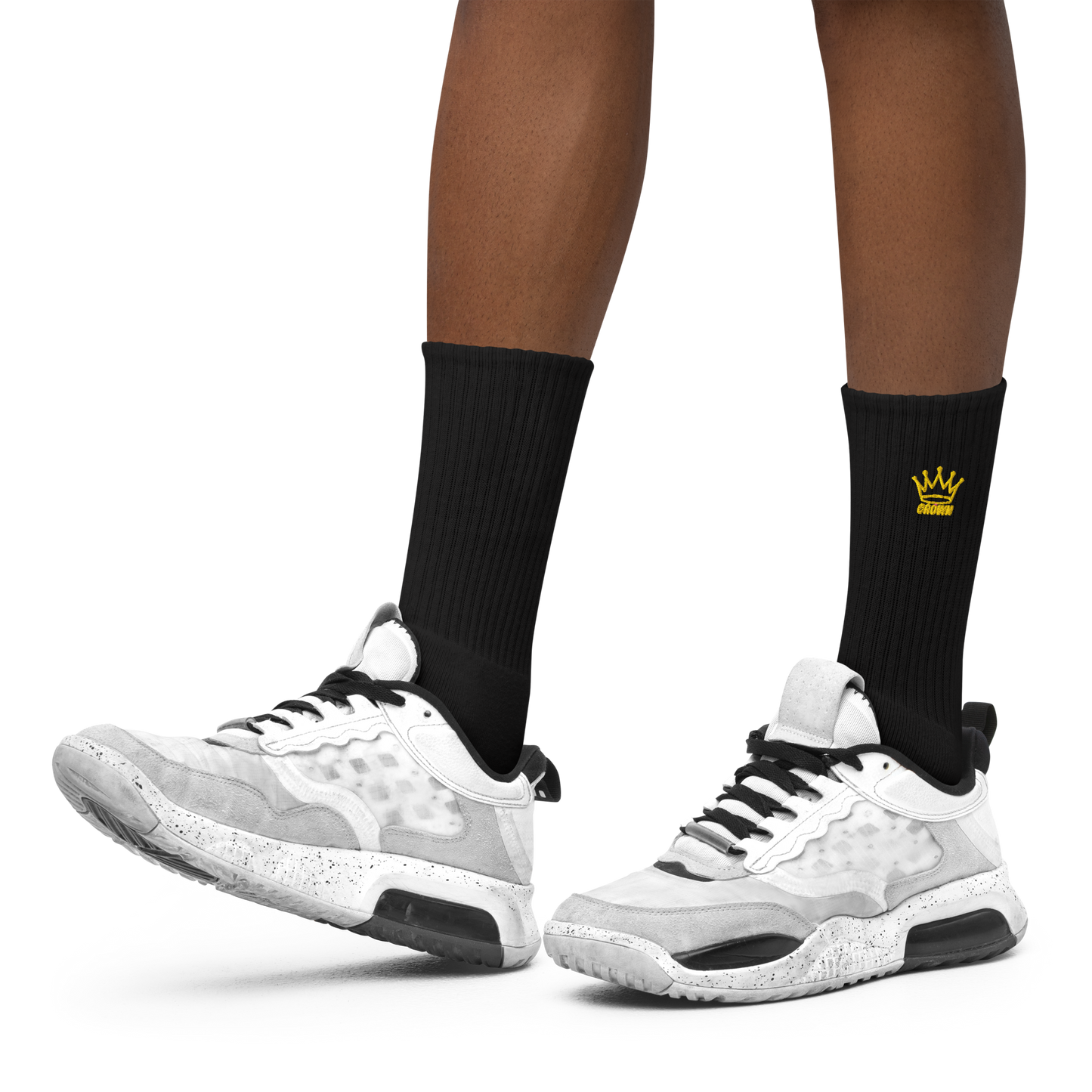 A close-up of a person wearing Crown Pickleball’s CROWN PICKLEBALL - Embroidered Logo Socks (Black) featuring a yellow crown logo and cushioned sole, paired with white sneakers with black accents, on a plain white background.