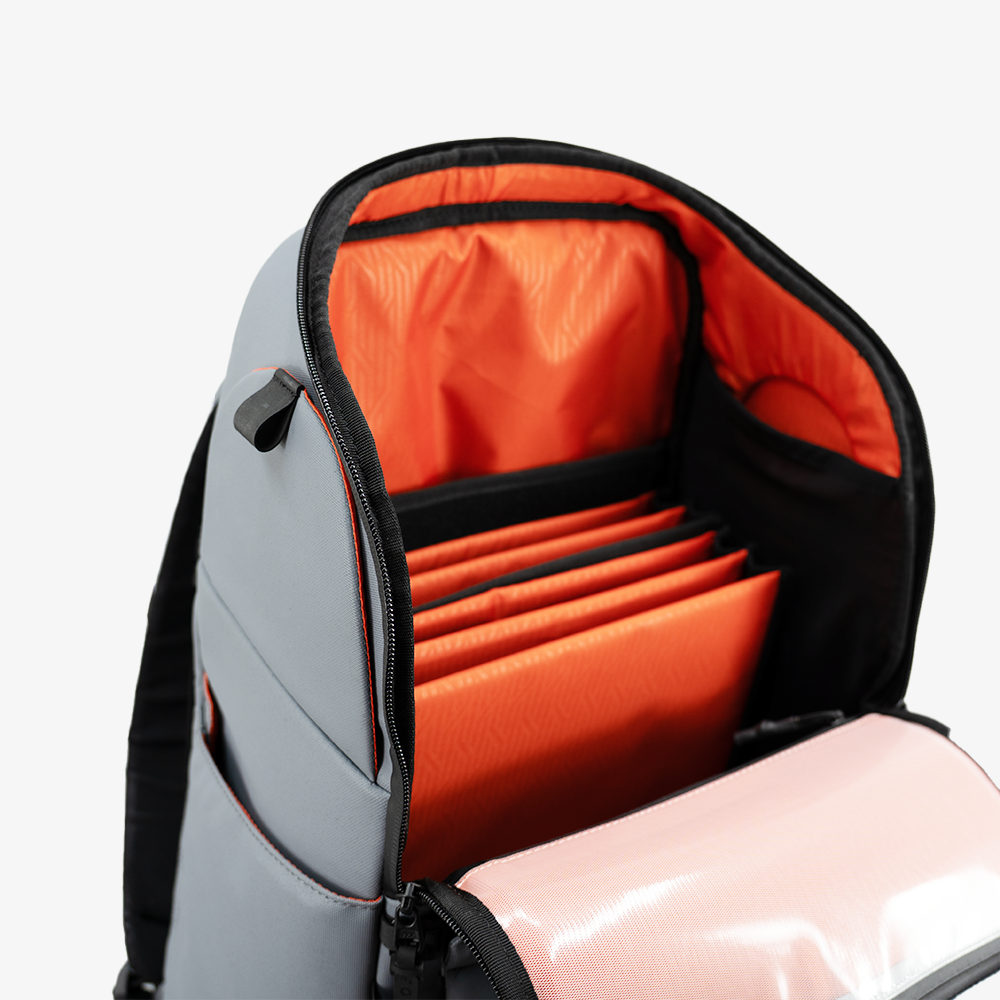 The FORWRD Court Caddy Pickleball Bag is a gray backpack with black edging, a sleek modern design, an orange interior with accordion-style dividers for organization, and a side pocket.
