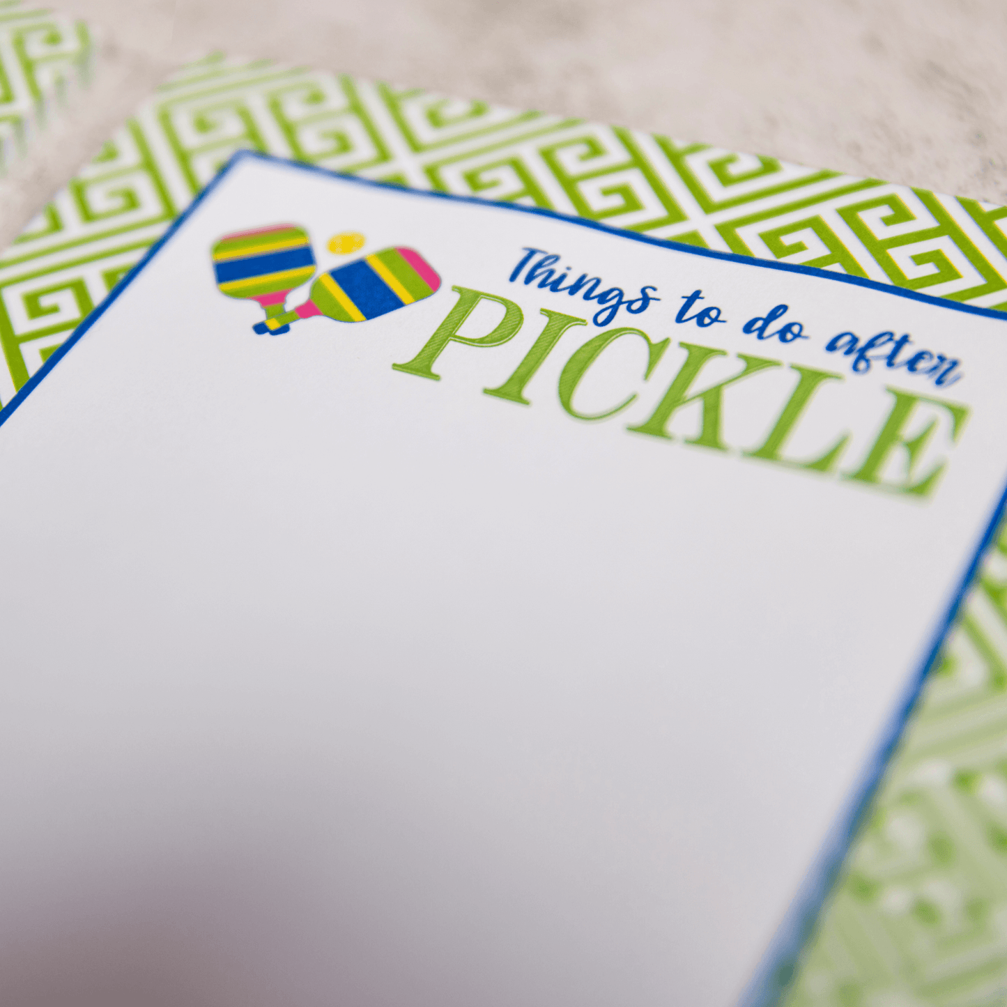 The Fresh Pickle Pickleball Notepad features a green and blue geometric border, a “Things to do after PICKLE” heading with paddle and ball illustrations, and a blank writing area—ideal for enthusiasts or as unique pickleball gifts.