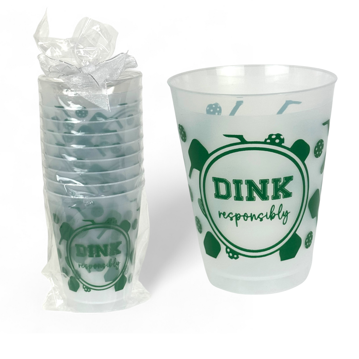 A clear bag with a white ribbon holds a stack of Fresh Pickle’s Pickleball Roadie Cups, plus one cup beside it. Both feature playful green pickleball paddles, balls, and “DINK responsibly” on translucent shatterproof plastic. White background.