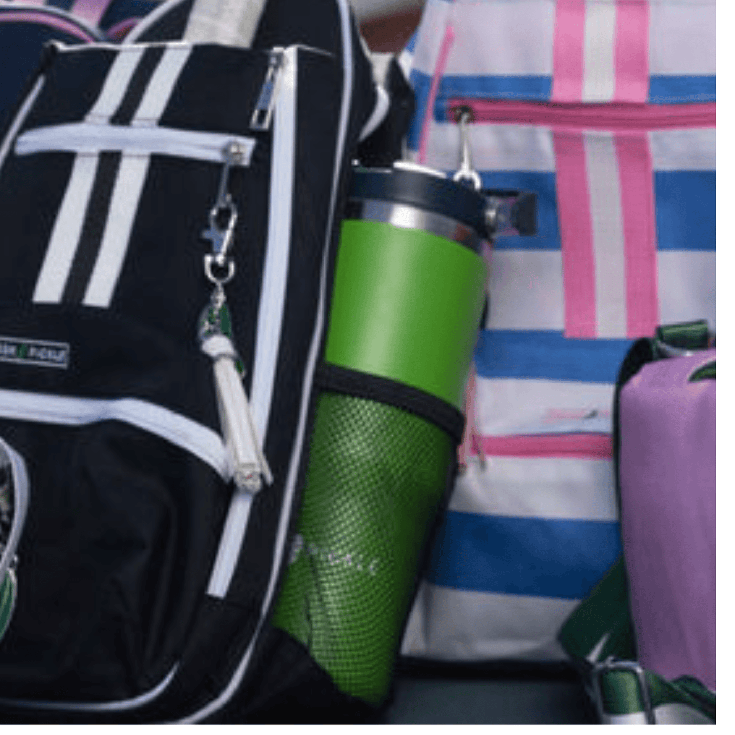 A close-up of two backpacks—one black with white stripes and zippers, holding a Fresh Pickle Tumbler by Fresh Pickle in a mesh pocket, and one white with pink and purple plaid, both side by side against a neutral background.