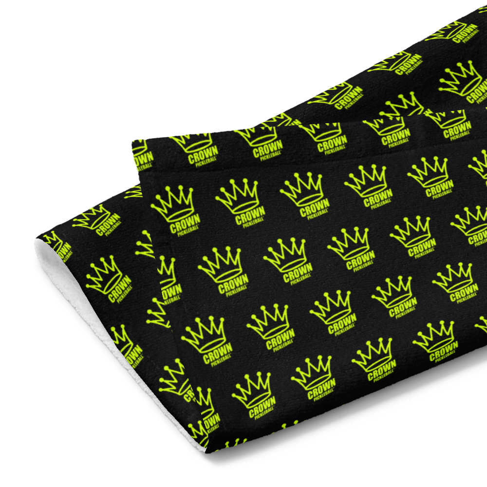 The Crown Pickleball Corona Pattern Hand Towel (BLACK) by Crown Pickleball features a folded cotton design with an even pattern of yellow crowns and bold "CROWN" text on a solid black background, adding a stylish touch to your game.