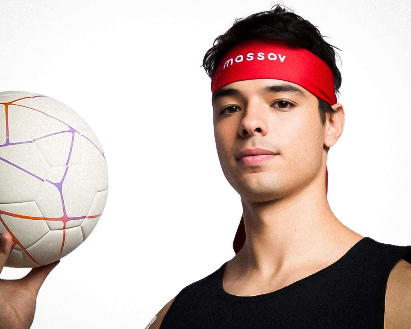 A young person wears a black tank top and a red Massov Headband Tie, holding a white volleyball with colorful lines. They face the camera confidently against a plain white background.