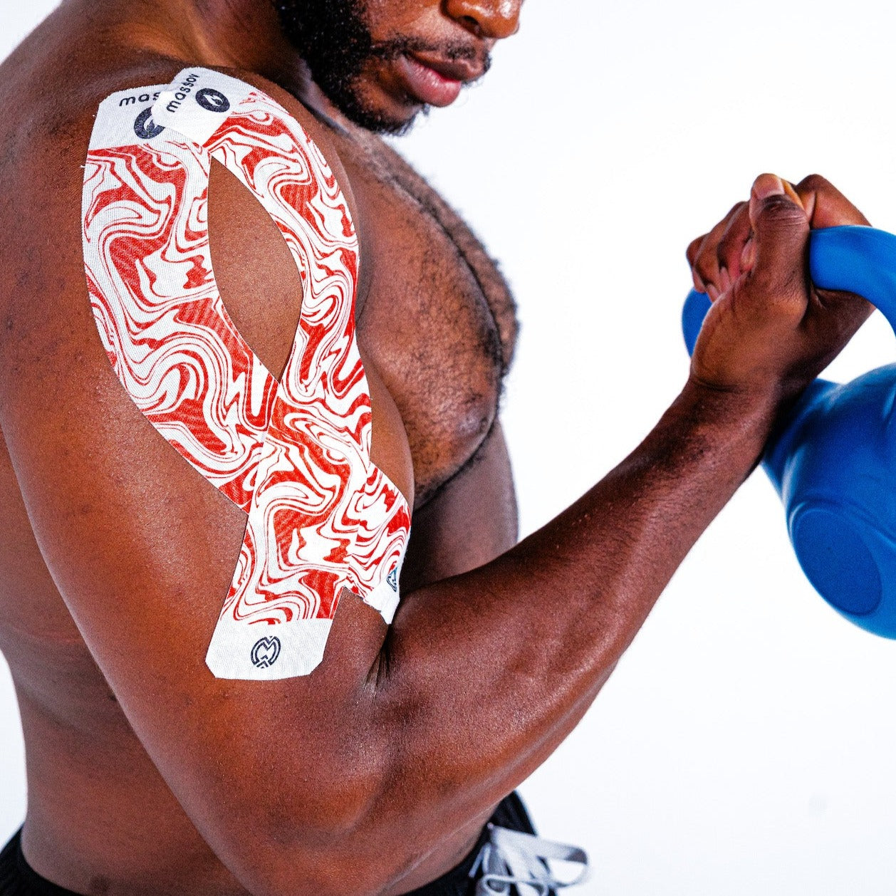 A muscular man lifts a blue kettlebell with his right arm, showing Massov's Heat Therapy Kinesiology Tape applied to his upper arm and shoulder for support. The plain white background highlights athletic activity and muscle pain relief.
