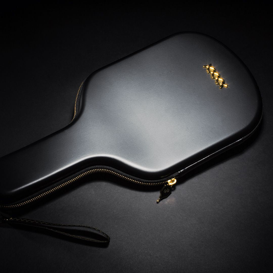 The Dope Pickleball Co. High Roller Pickleball Paddle Travel Case features sleek black vegan leather, rounded edges, a gold zipper, wrist strap, and gold logo—offering premium protection and style for your paddle.