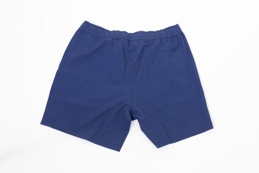 A pair of Thrive Elite Shorts (7 in.) by Thrive Pickleball in navy blue rests flat on a white surface, back view. Lightweight fabric and an elastic waistband provide comfort, while two back pockets—one with a buttonhole—add practicality.
