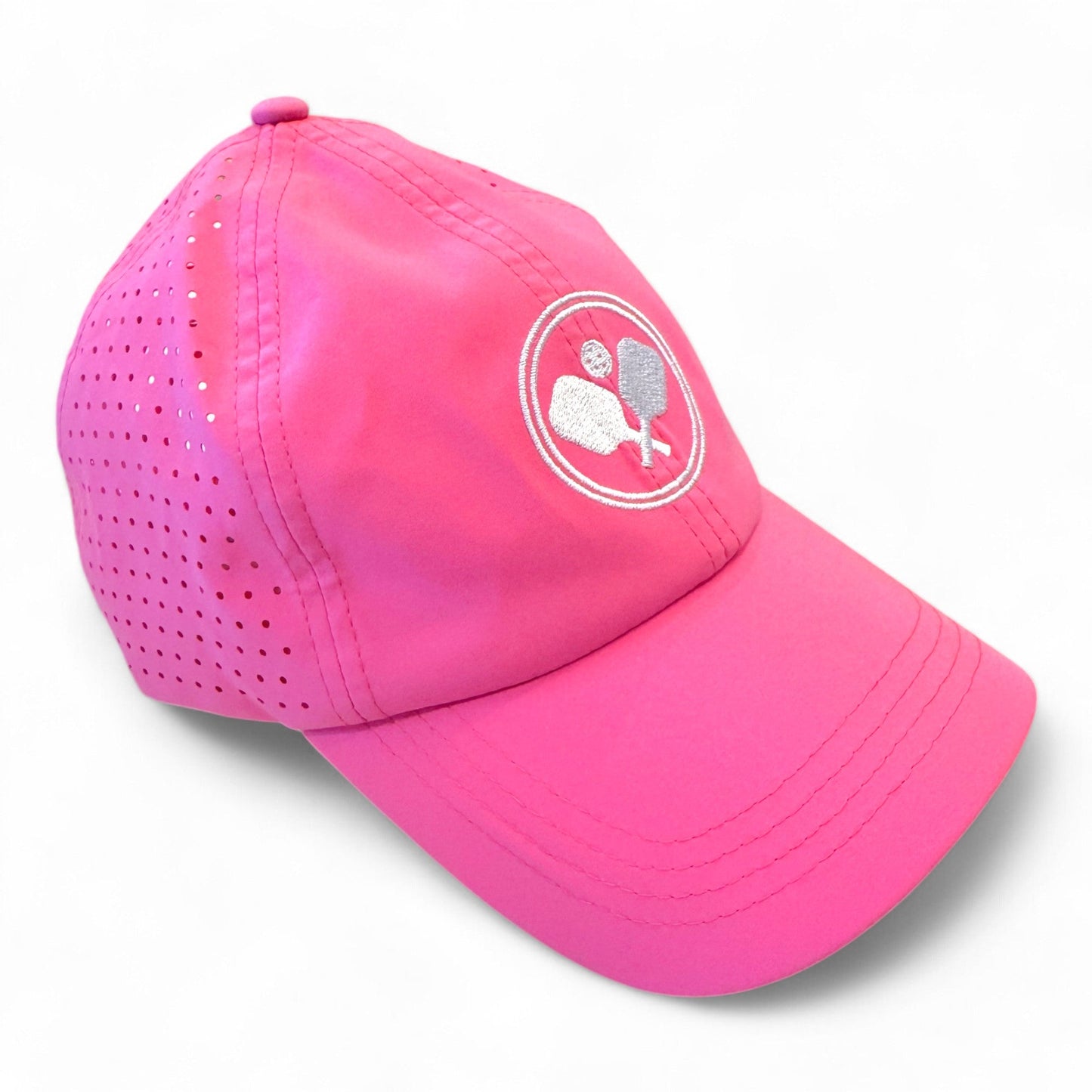 The Fresh Pickle Pickleball Caps are bright pink, breathable, and feature side ventilation holes plus a white embroidered logo of two crossed paddles with a pickleball on the front, shown on a plain white background.