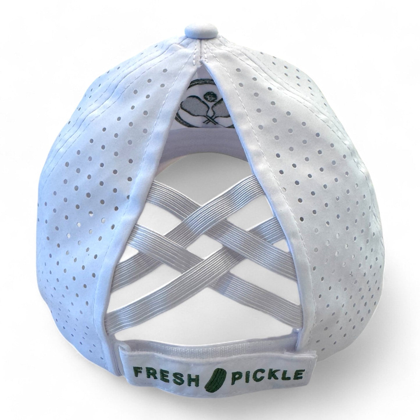 The Fresh Pickle Pickleball Cap is a white, breathable sports cap with perforated panels, overlapping elastic bands at the back, an embroidered green pickle and “FRESH PICKLE” text, plus a pickleball paddle and ball illustration inside.