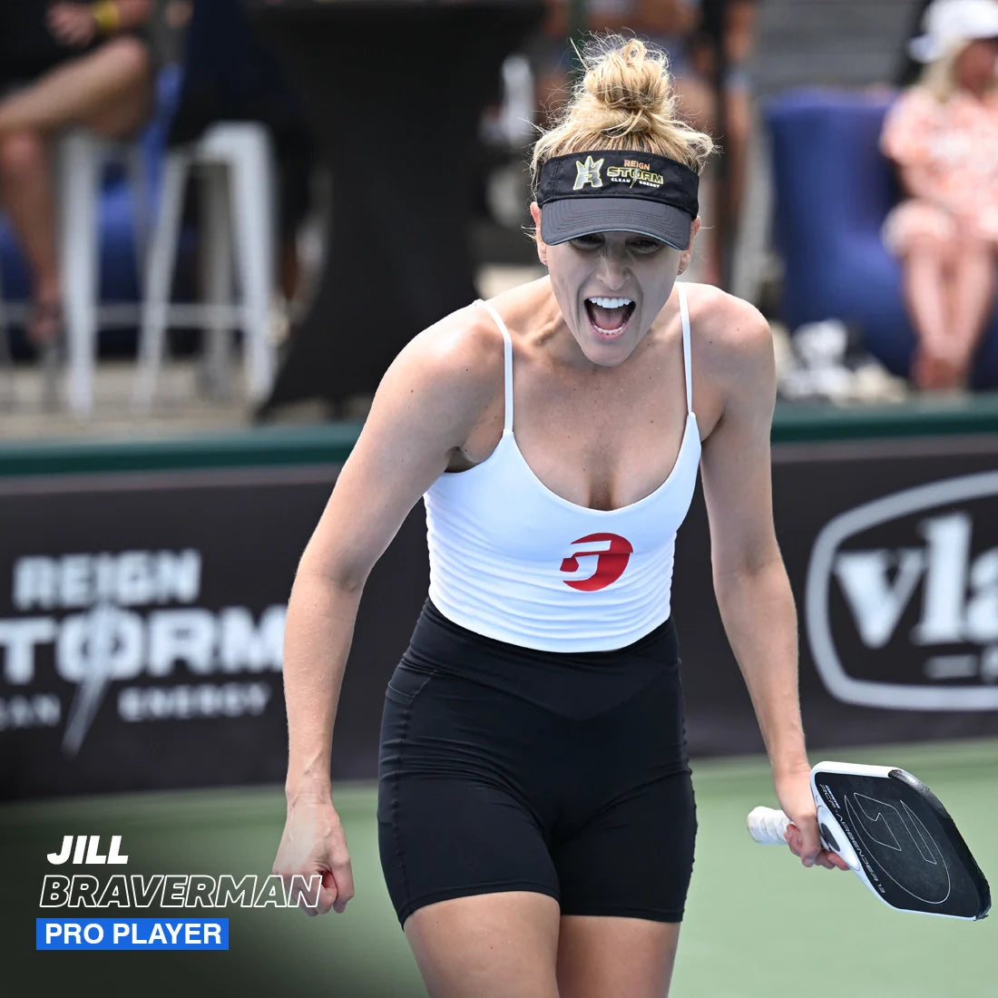 A female pickleball player wearing a white tank top, black shorts, and a black visor energizes the court as she shouts holding the Hesacore Grip Pickleball Elongated Grip—6 Inches Long, Regular Feel, White. “Jill Braverman Pro Player” text appears.