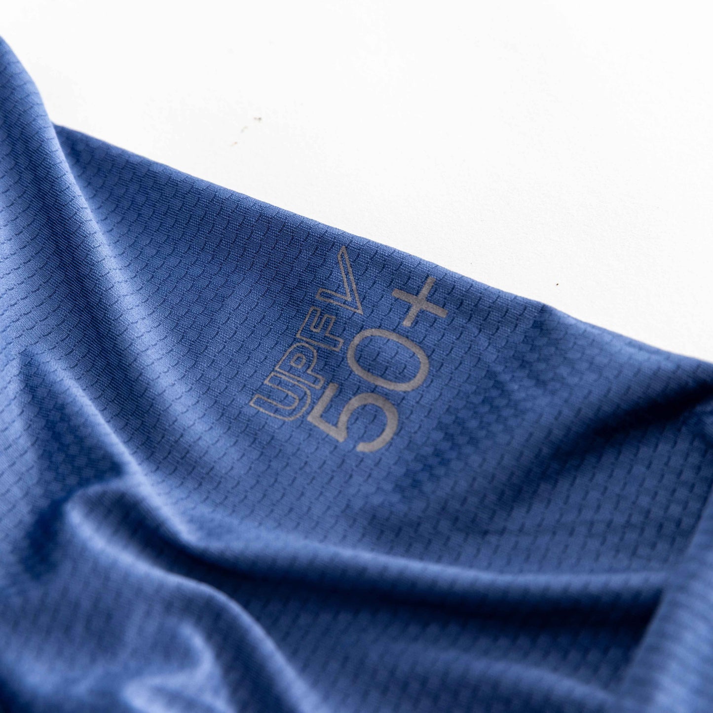 A close-up of Swinton Pickleball’s Navy Zip-Front Sun Hoodie shows lightweight blue fabric with a subtle grid, “UPF 50+” printed in gray, highlighting its sun protection and breathable design against a white background.