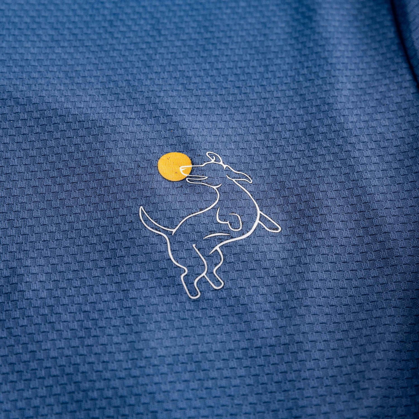 A close-up of the Navy Zip-Front Sun Hoodie by Swinton Pickleball shows its blue textured, breathable fabric with a white line drawing of a playful dog and yellow ball, combining stylish grid pattern and sun protection for comfort and fun.