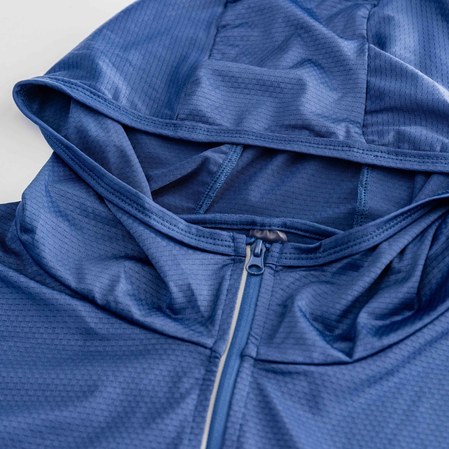 Close-up of the Swinton Pickleball Navy Zip-Front Sun Hoodie, featuring UPF 50+ lightweight, textured fabric with a subtle geometric pattern. The hood is laid flat and the zipper is partially visible, highlighting stitched seams for added sun protection.