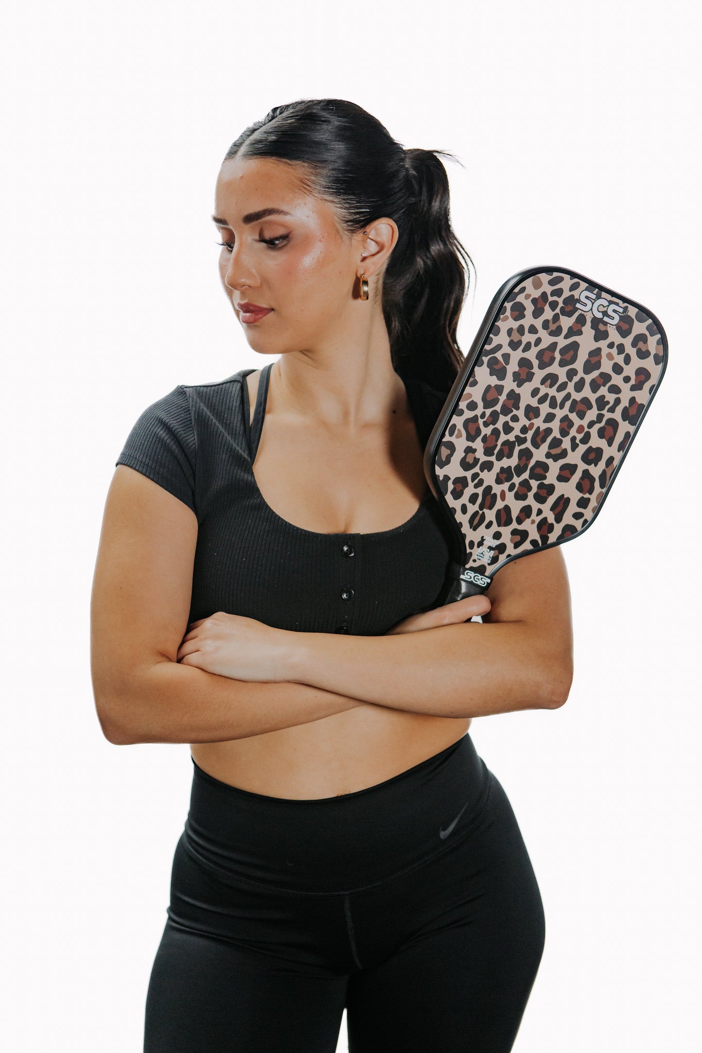 A woman holding a Salted City Sports Leopard | Evo-Lite Series pickleball paddle, USA Pickleball Approved.