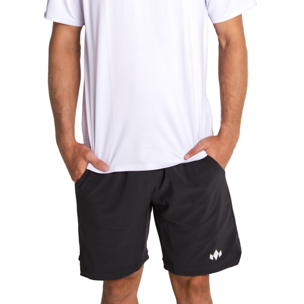 Wearing a plain white short-sleeve shirt and Diadem Sports Men's Essential 8" Short, featuring a small white logo on the left leg, a person stands with hands in pockets against a white background. Head and lower legs are not visible.