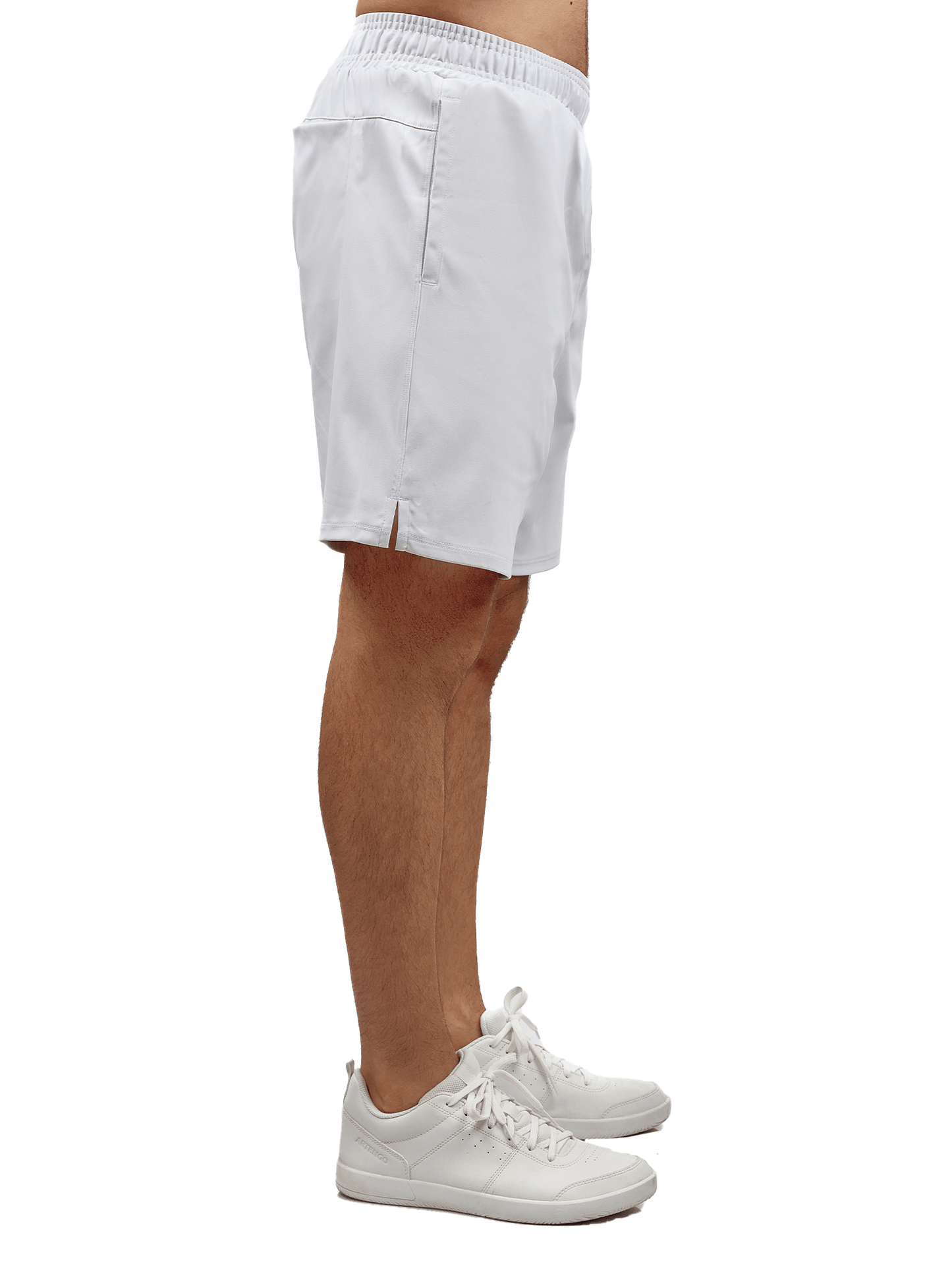 A person stands in profile wearing inPhorm NYC Men's Tennis Spin Shorts with Pockets & UV Protection in white, featuring an elastic waistband, side pocket, small hem slit, and sneakers. The plain white background highlights the shorts.