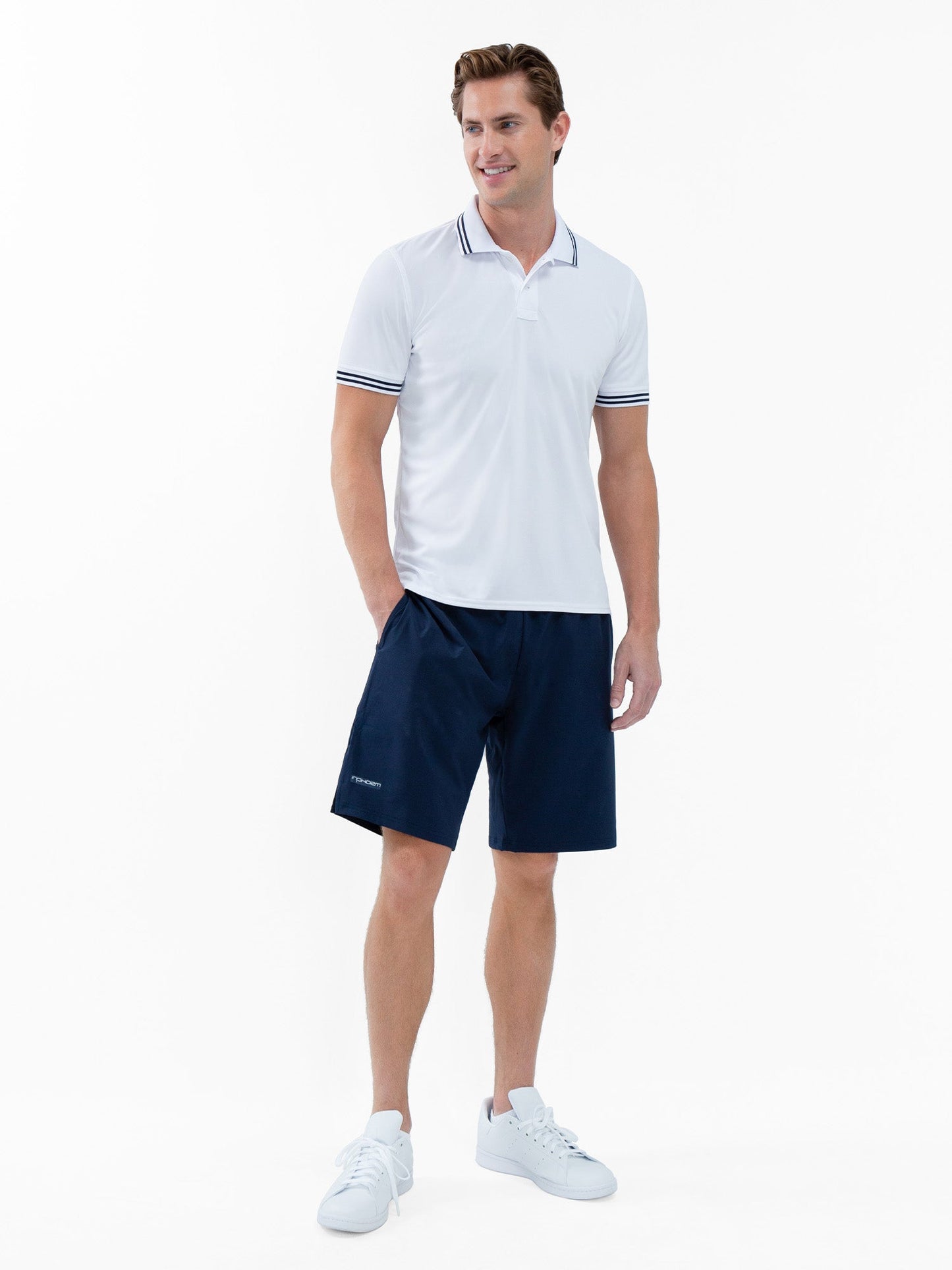 A man smiles against a white background, wearing the inPhorm NYC Performance Men's Classic Tennis Rib Collar Polo in White/Midnight. This stylish polo offers UV protection and moisture wicking—perfect for sunny days on or off the court.