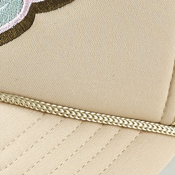 Close-up of the ARTI Pickle Me Trucker Hat, showing neat stitching, a gold braided trim above the brim, and part of an embroidered mint green, pink, and dark brown design—ideal for active pickleball enthusiasts.