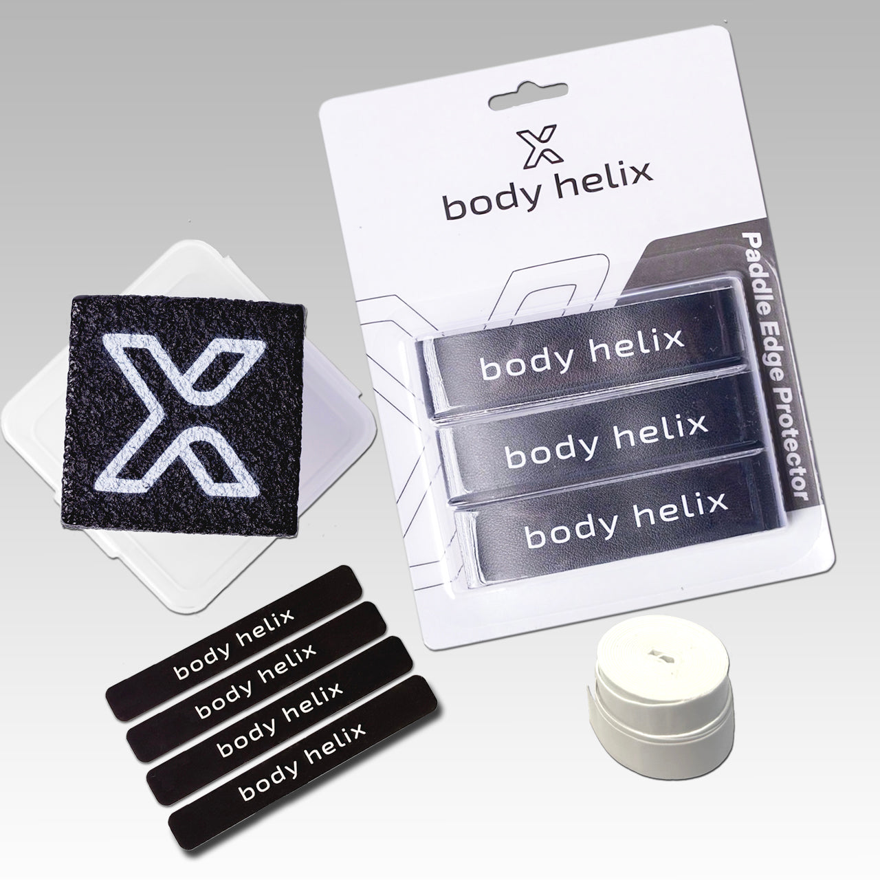 The body helix Pickleball Paddle Accessory Kit on a gray background features three paddle edge protectors, a black patch with a white X logo, a small round paddle eraser, and branded body helix packaging.