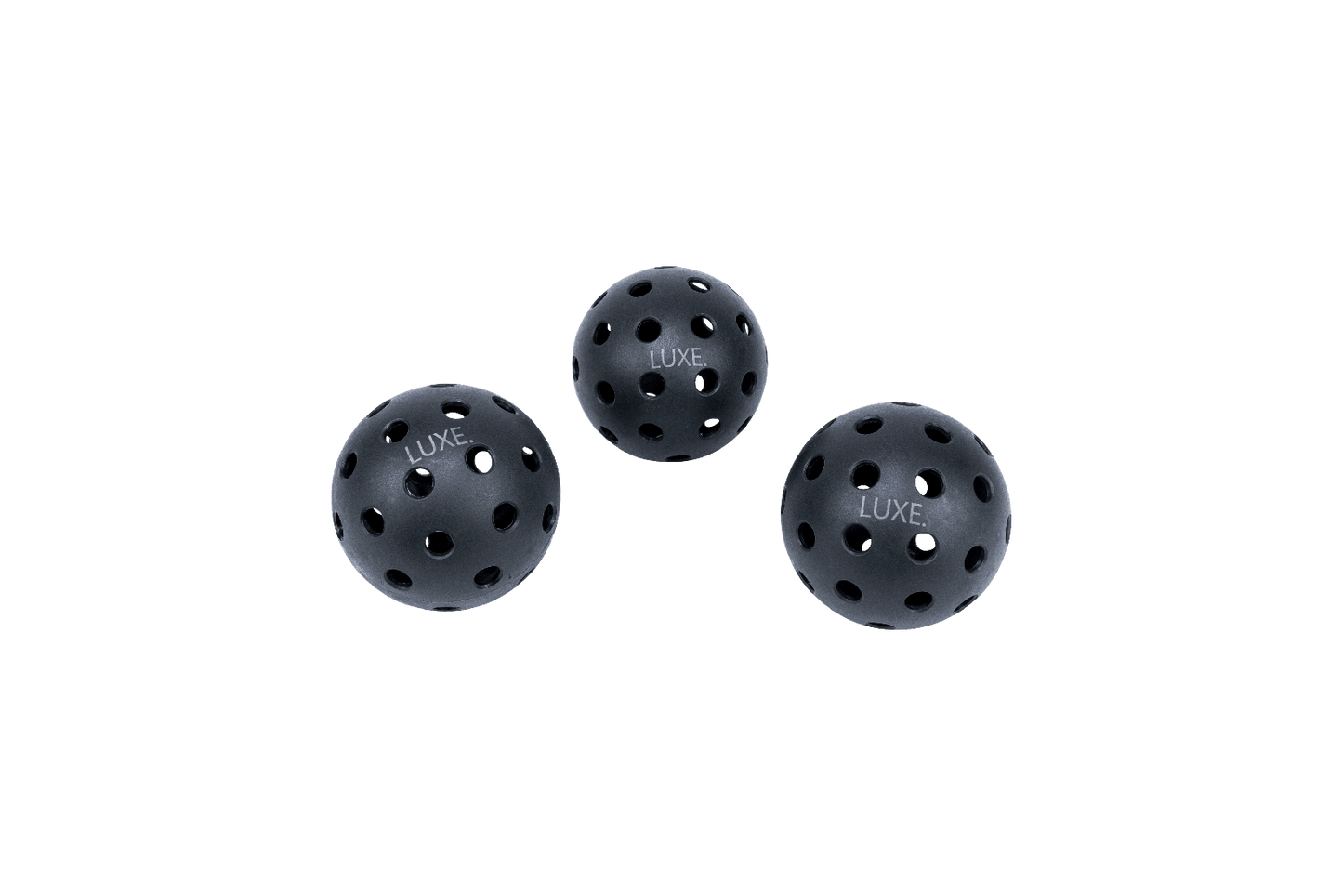Three black LUXE Pickleballs by LUXE Pickleball, designed for indoor and outdoor play, are arranged in a triangle. Each durable ball features evenly spaced holes and "LUXE" printed in white on the surface.