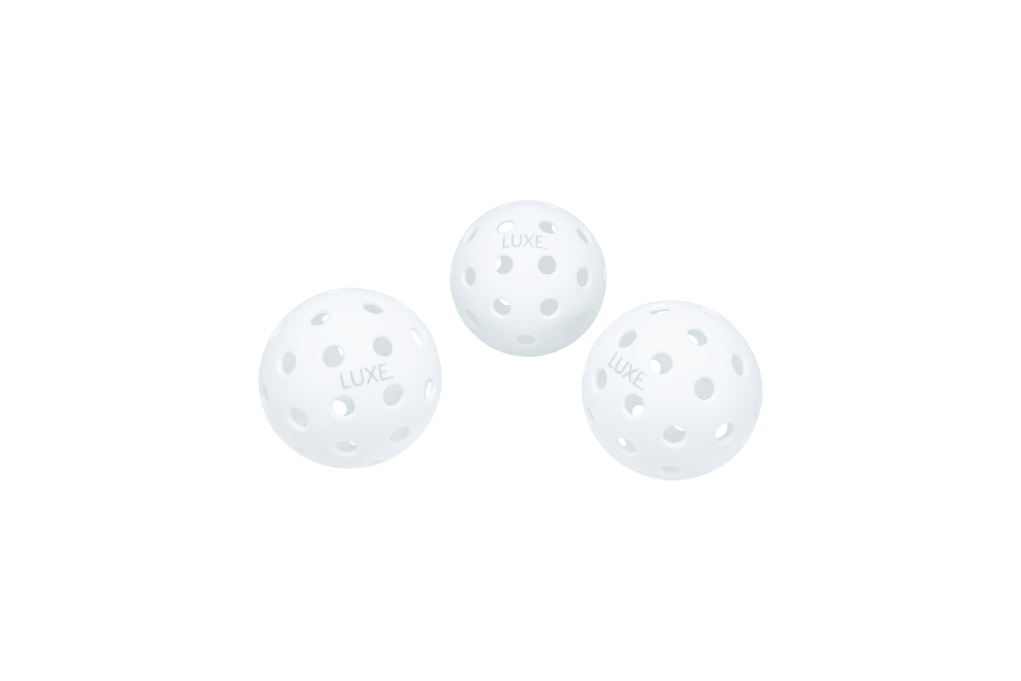 Three white LUXE Pickleballs from LUXE Pickleball, designed for indoor and outdoor play, are shown on a plain white background in a triangle formation with "LUXE" printed on each durable ball.