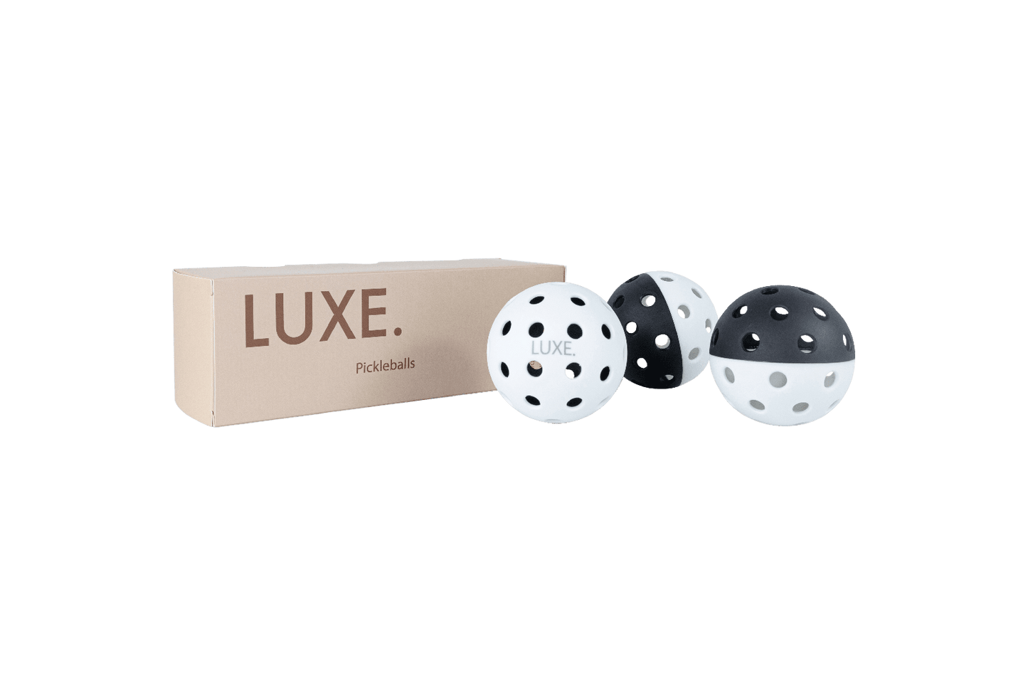 A beige LUXE Pickleball box is shown beside three durable LUXE Pickleballs—white, black-and-white, and black—each with evenly spaced holes, designed for indoor and outdoor play. The background is plain white. Brand: LUXE Pickleball.