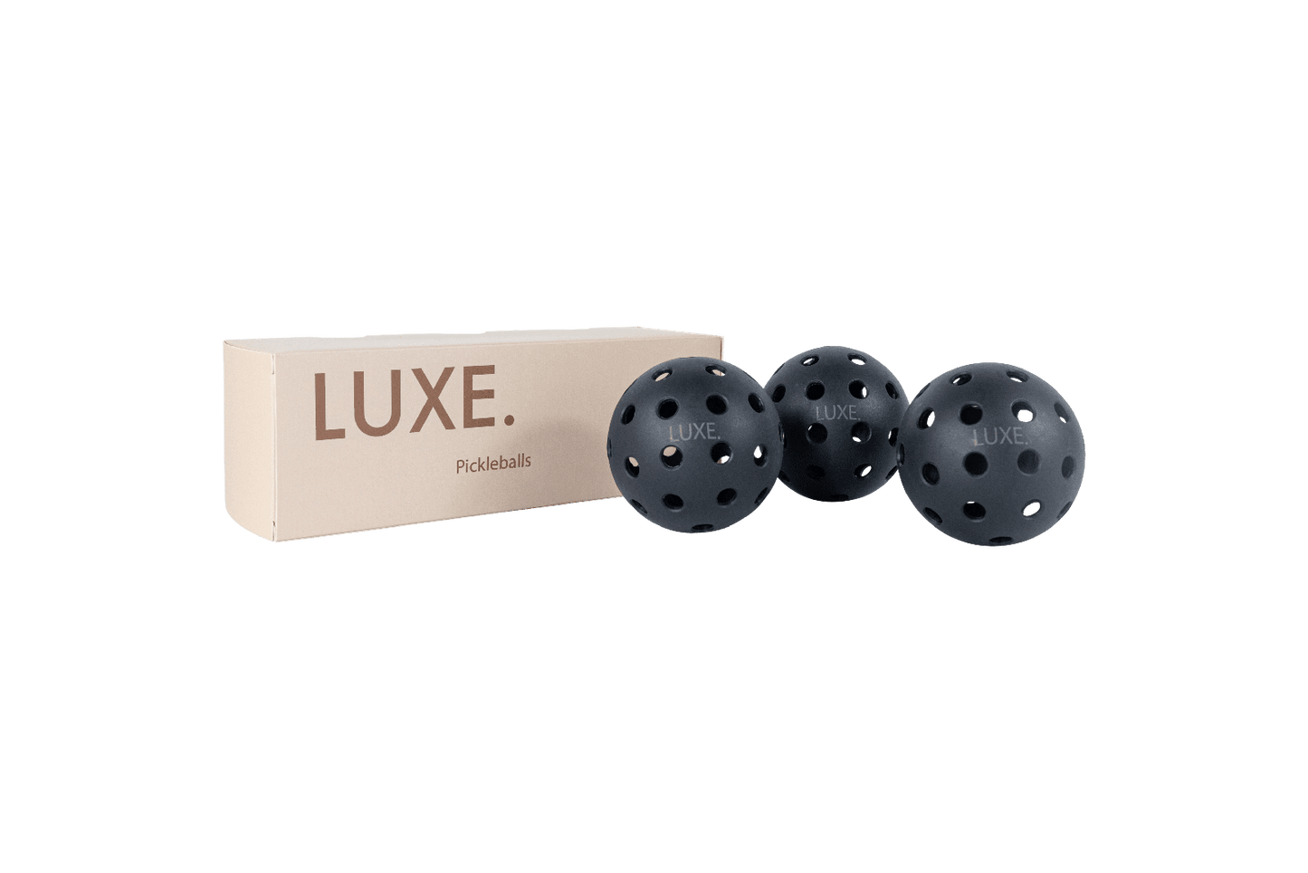 A beige rectangular LUXE Pickleball box sits next to three black LUXE Pickleballs—durable indoor and outdoor balls with multiple holes—arranged in a row against a plain white background.