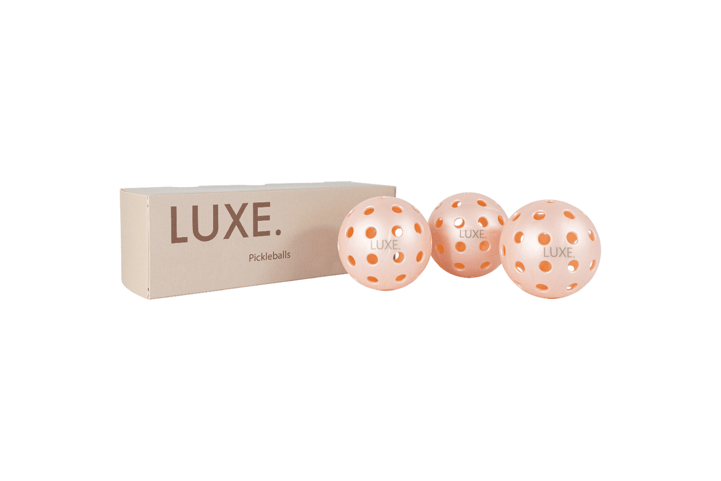 A beige rectangular LUXE Pickleball box sits beside three pink 40-hole pickleballs, each marked "LUXE," against a plain white background.