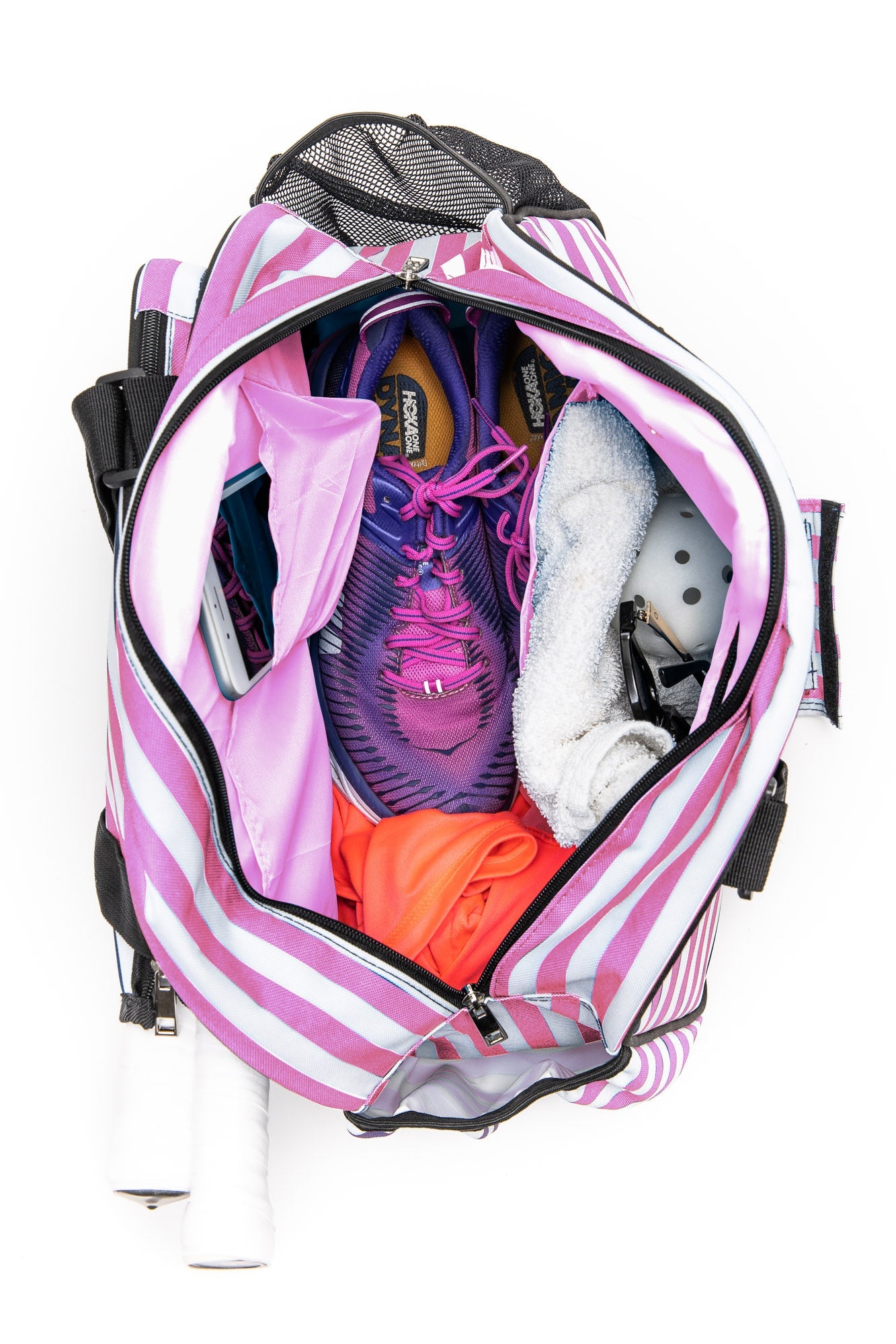 The Stylish Stripe Premium Women's Pickleball Bag by Pik'le'Ball Sports is shown unzipped from above, with organizer pockets neatly holding purple running shoes, a towel, orange workout clothes, a smartphone, Crocs, and two racquets.