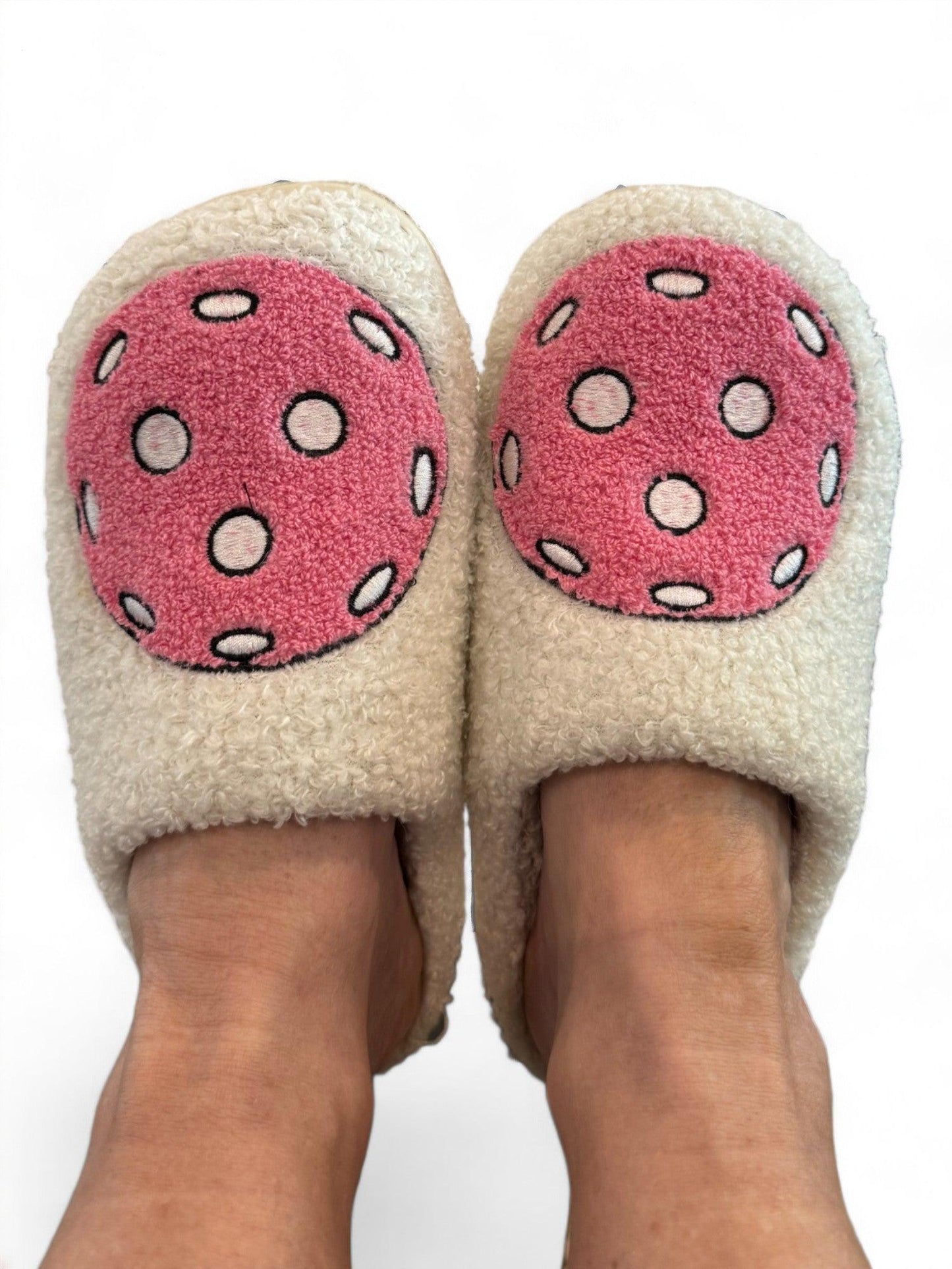 A pair of feet wearing Fresh Pickle's Pickleball Slippers in cream, featuring large pink circles and white dots resembling cartoon mushrooms, shown against a white background.