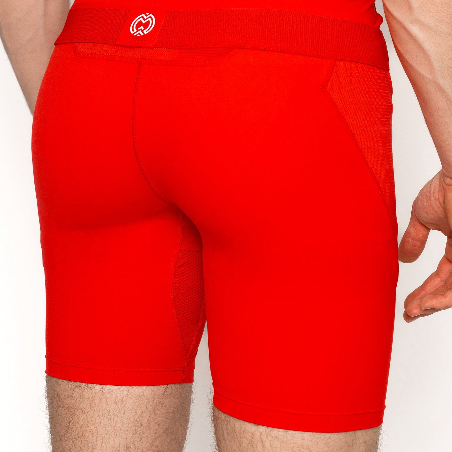 A Massov ProForm® Boys' 7″ Compression Shorts is shown from waist to mid-thigh, facing away. The bright red shorts have side mesh panels and a small white logo at the center waistband. The model's skin is light.