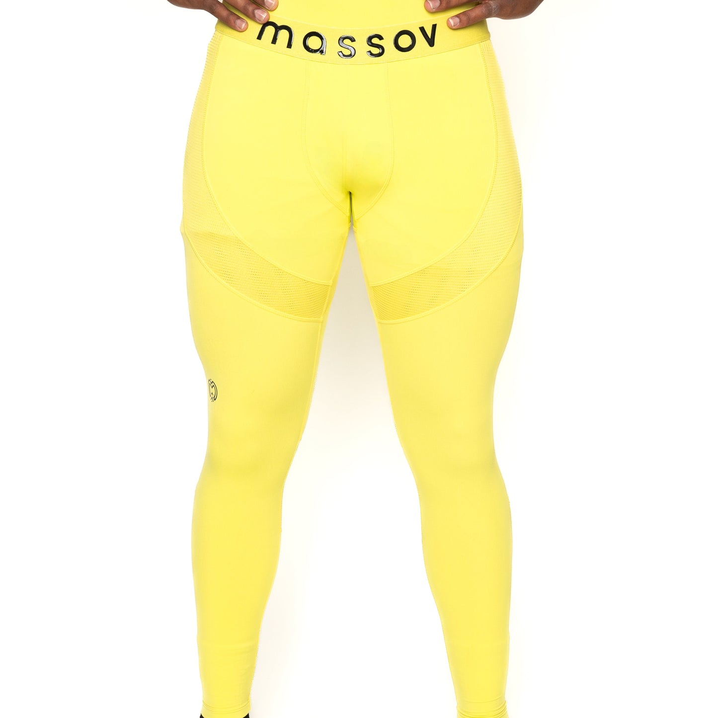 A boy wears bright yellow Massov ProForm® Boys' Compression Pants with mesh thigh panels and a black "massov" waistband. His hands rest on his hips; only his body from waist to ankles is visible.