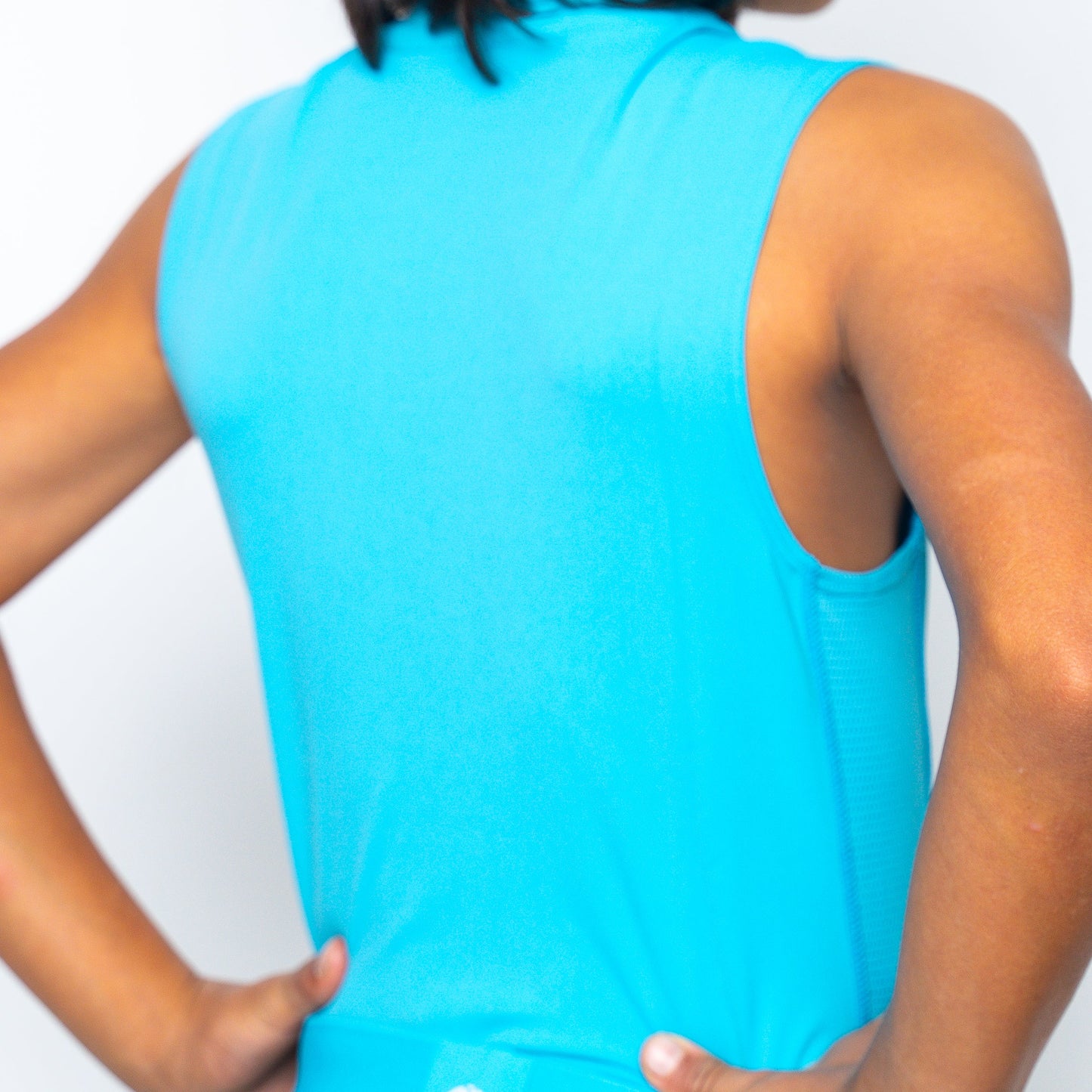 A person with medium skin tone, seen from the back, wears a Massov ProForm® Boys' Compression Tank Top in bright blue. Their short dark hair touches the shirt, and hands rest on their hips against a light background.