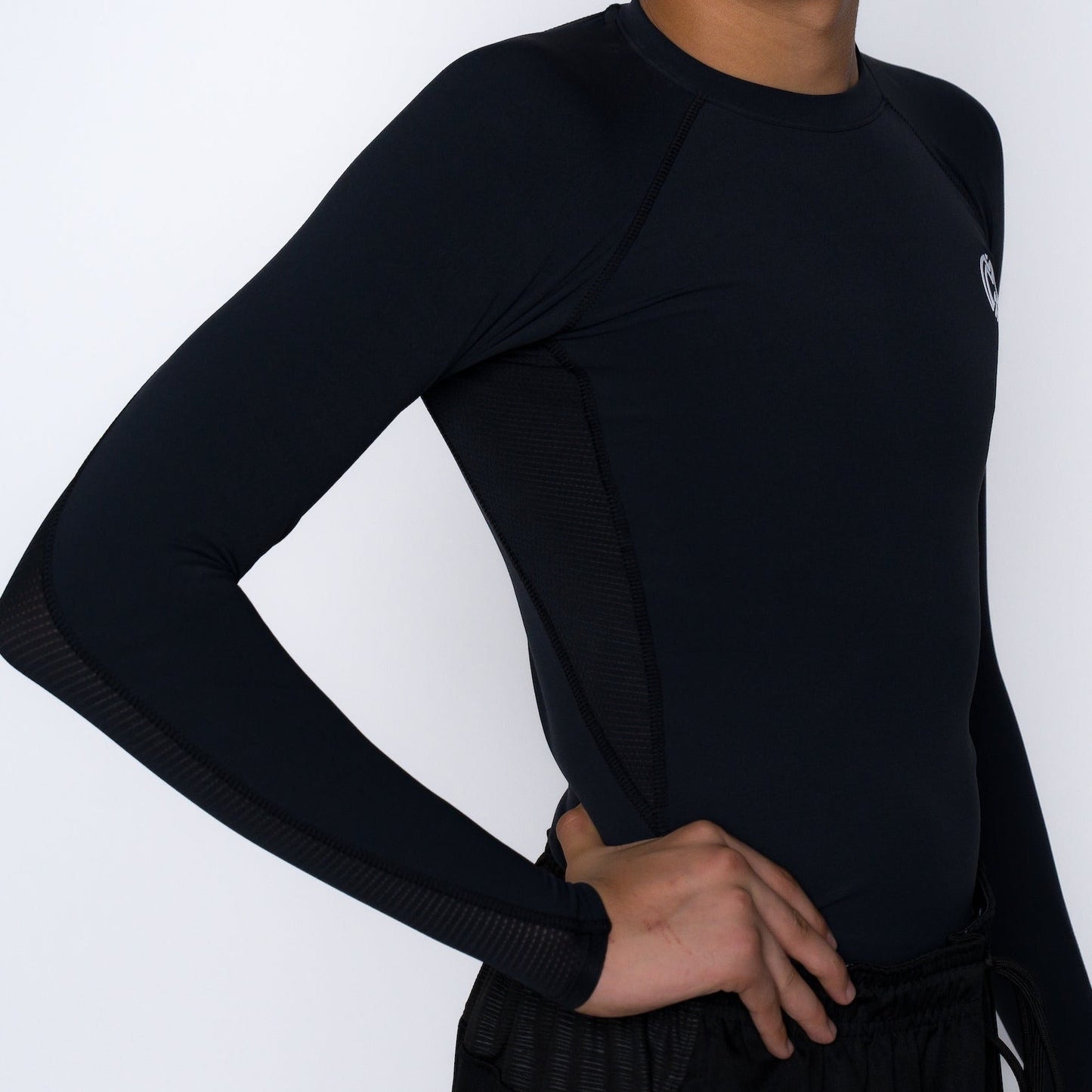 A model stands against a white background, hand on hip, wearing the Massov ProForm® Boys' Long Sleeve Compression Shirt with subtle mesh panels and small chest logo, paired with black shorts.
