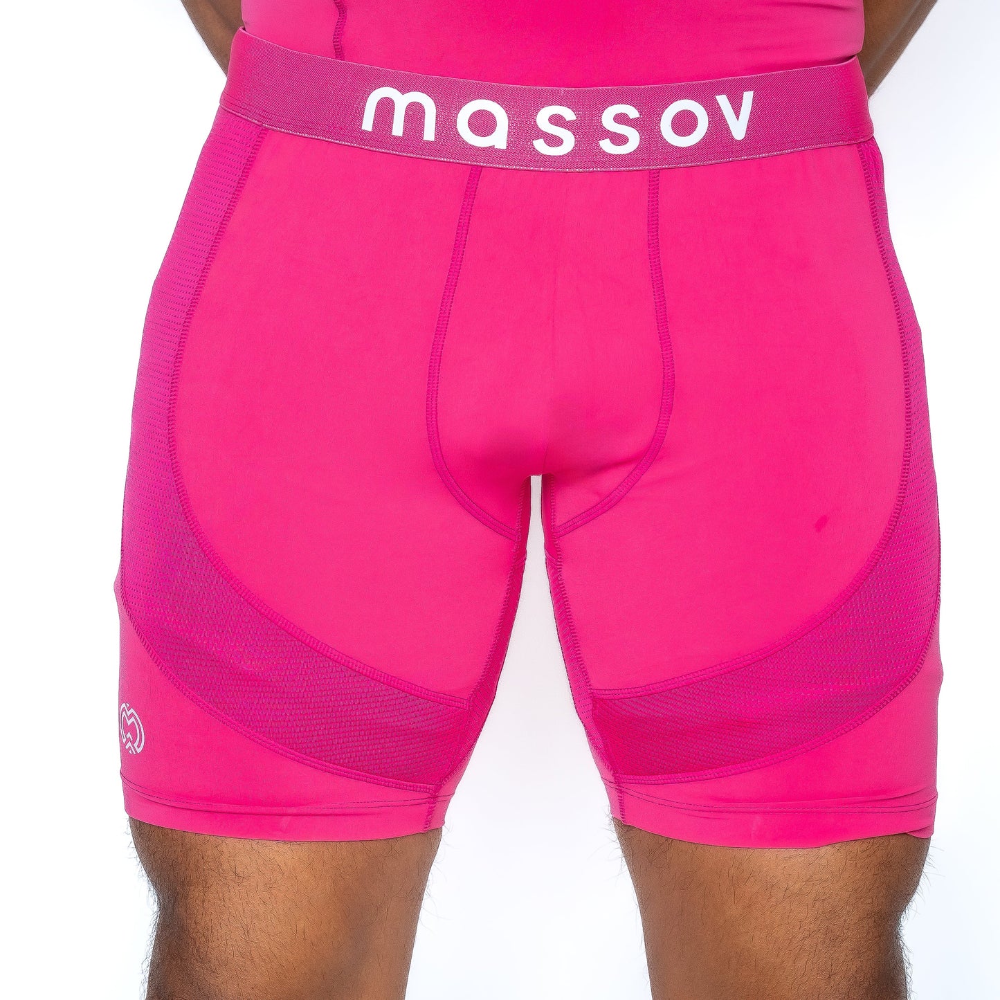A person wears Massov ProForm® Men’s 7″ Compression Shorts, bright pink with “massov” in white on the waistband, featuring mesh panels and contour stitching, shown cropped from waist to mid-thigh.