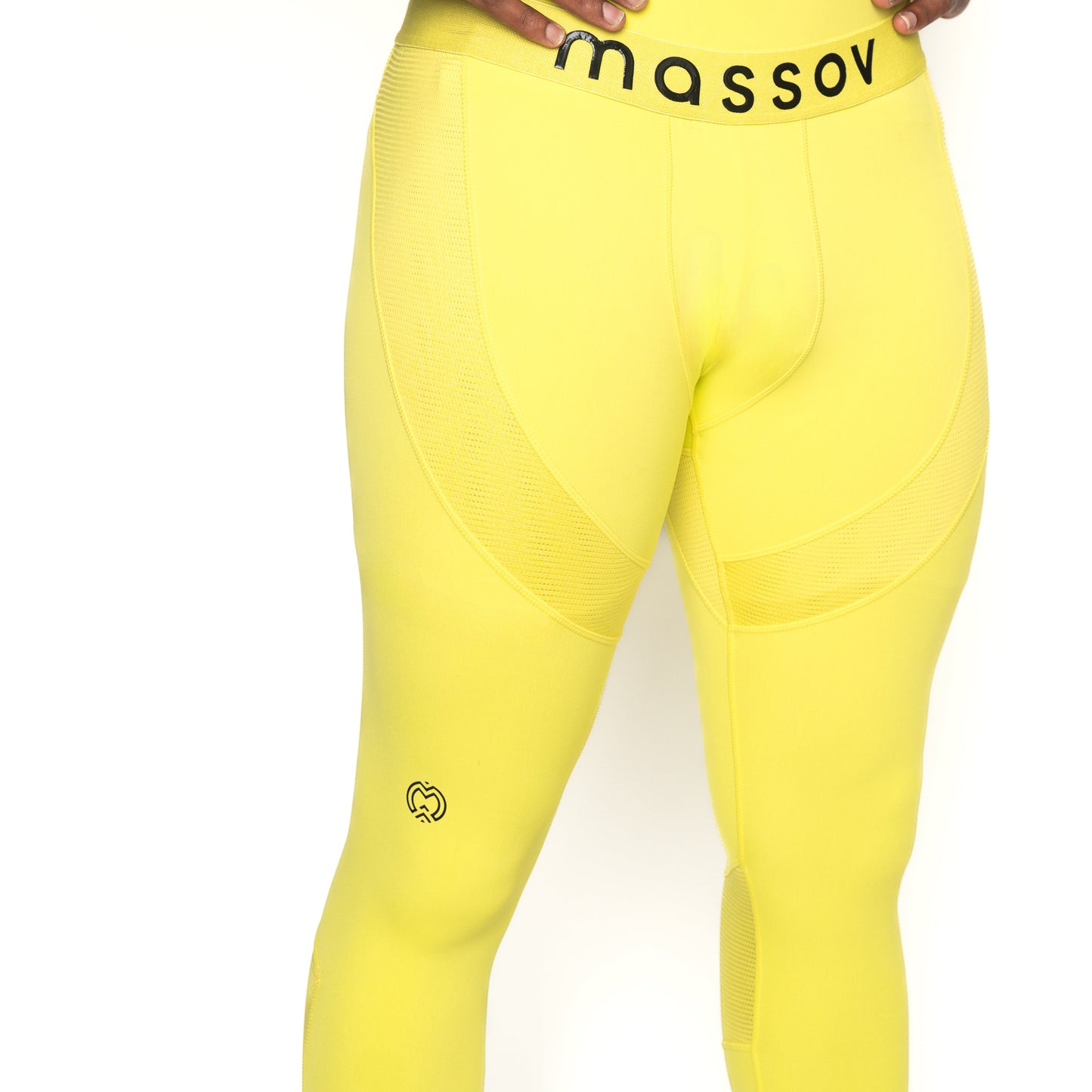 A person wears ProForm® Men's Compression Pants by Massov in bright yellow. The waistband displays "massov" in bold black letters, and a small black heart-shaped M logo is on the upper left thigh. Only the lower torso and legs are visible.