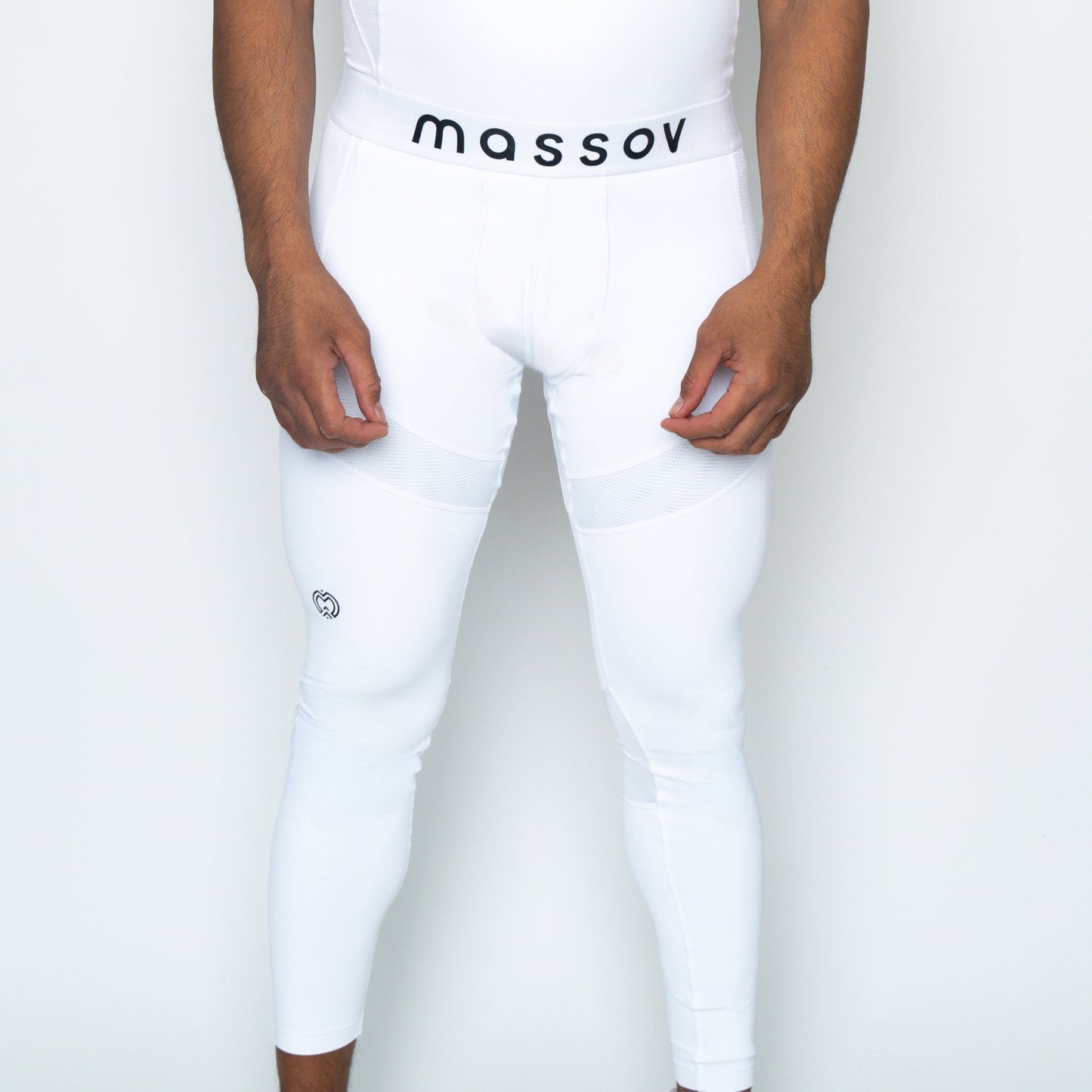 A person wears white ProForm® Men's Compression Pants by Massov, with the brand name on the waistband, subtle mesh panels, moisture-wicking fabric, and a small logo near the left knee. Only their legs are shown against a plain white background.