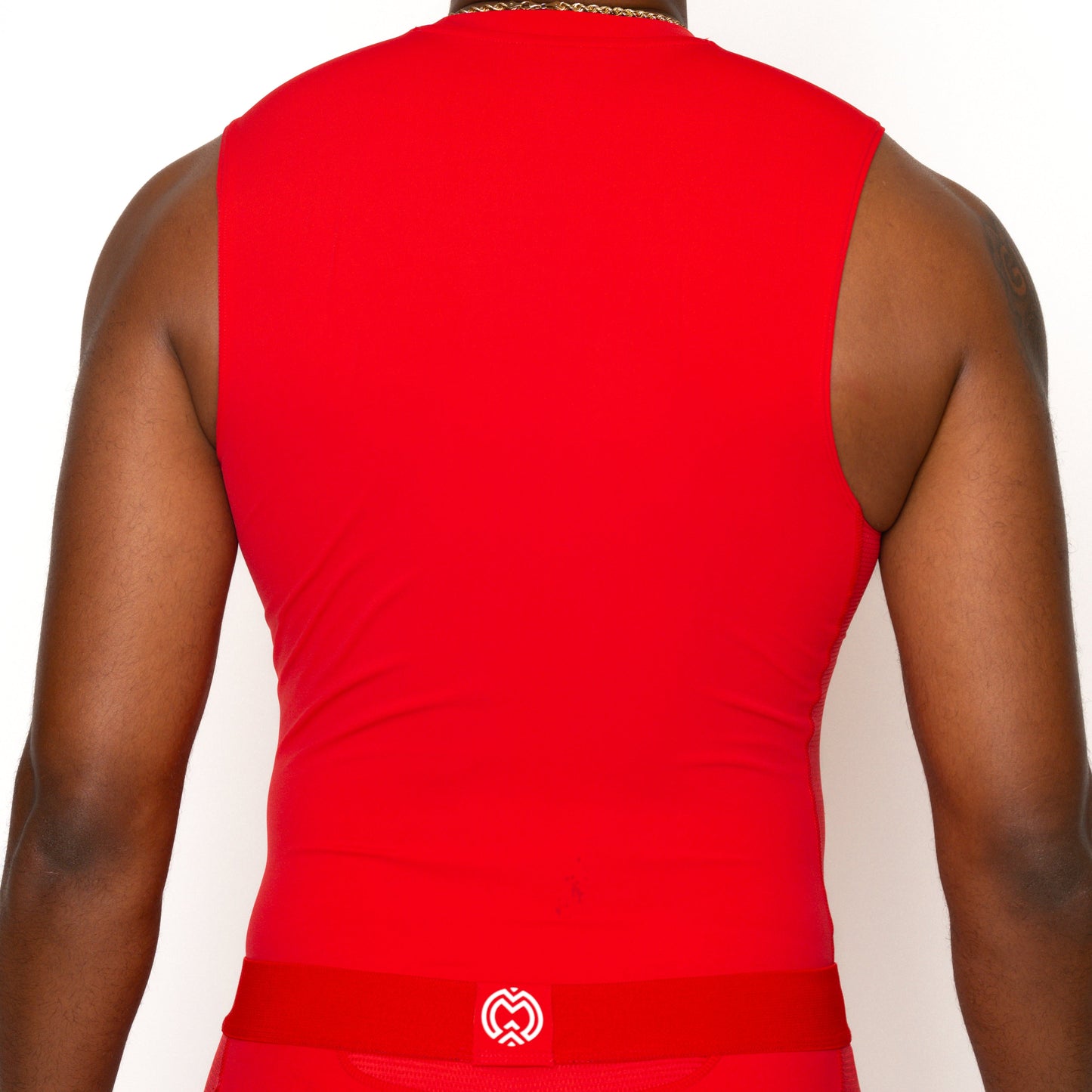 Seen from behind, a person wears the Massov ProForm® Men's Compression Tank Top in red with matching bottoms, featuring a small white logo on the waistband. The look is completed with a thin gold chain and a plain white background.
