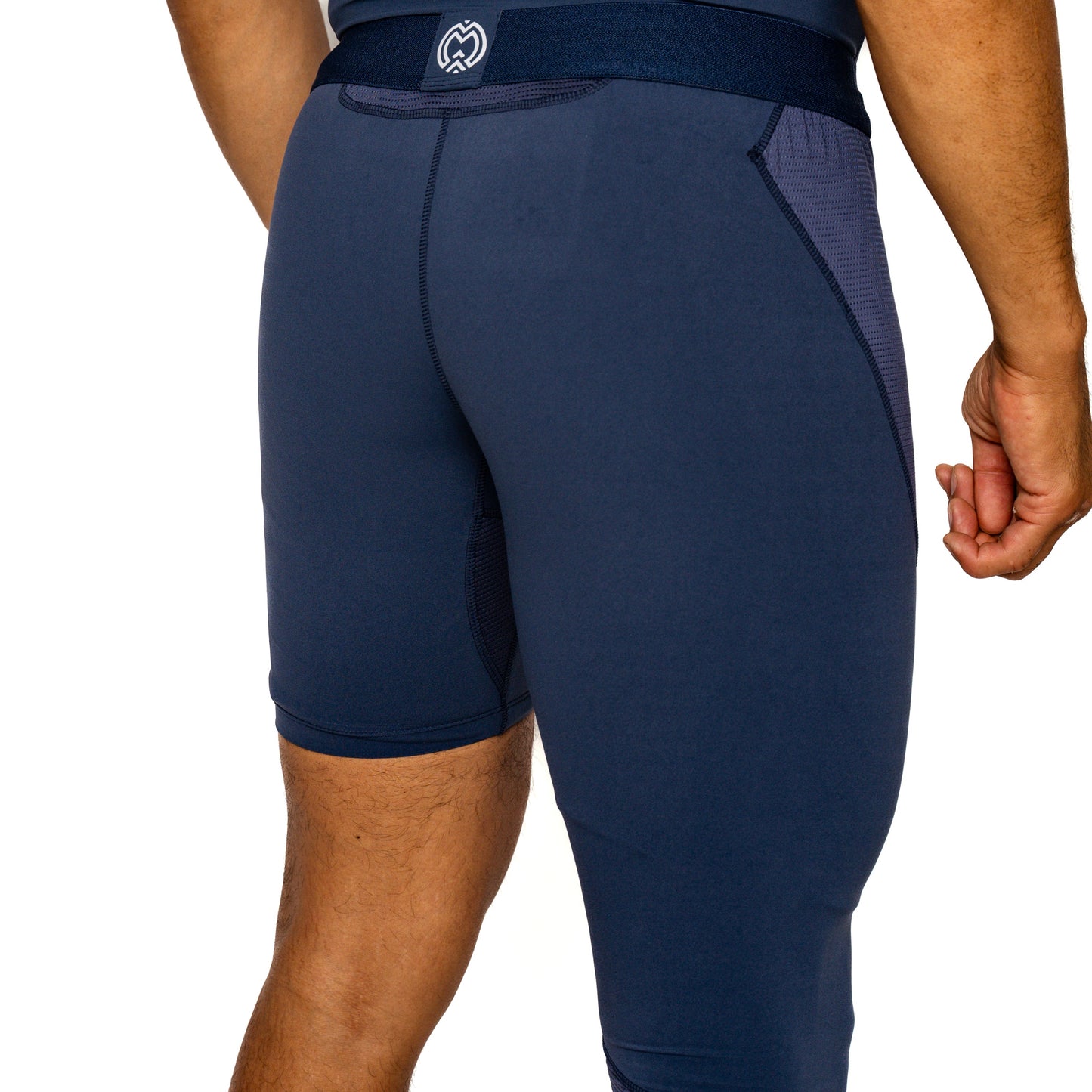 A close-up shows a person from the waist down in Massov ProForm® Men's One Leg Compression Pants, navy blue with side mesh panels, a fitted ProForm fabric design, and an elastic waistband featuring a white logo at the back.