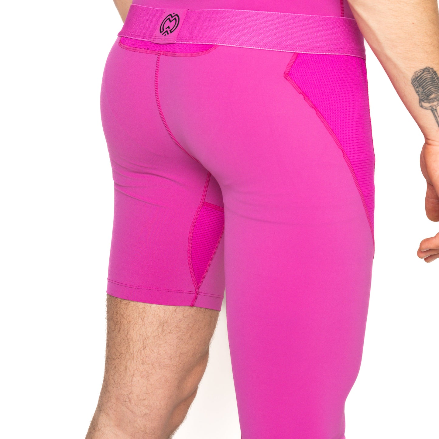 A person stands with their back to the camera, wearing Massov ProForm® Men's One Leg Compression Pants. The logo is visible, as well as part of their arm and a forearm tattoo. Plain white background.