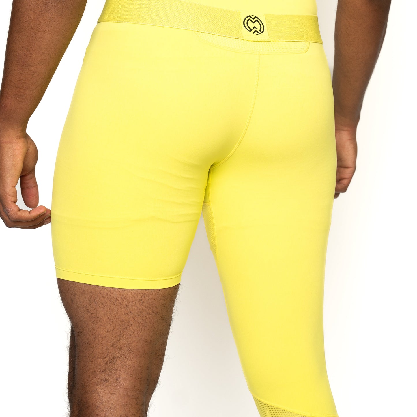 A person is shown from mid-back to mid-thigh wearing bright yellow Massov ProForm® Men's One Leg Compression Pants, made with ProForm fabric. A black logo appears on the back waistband, set against a plain white background.