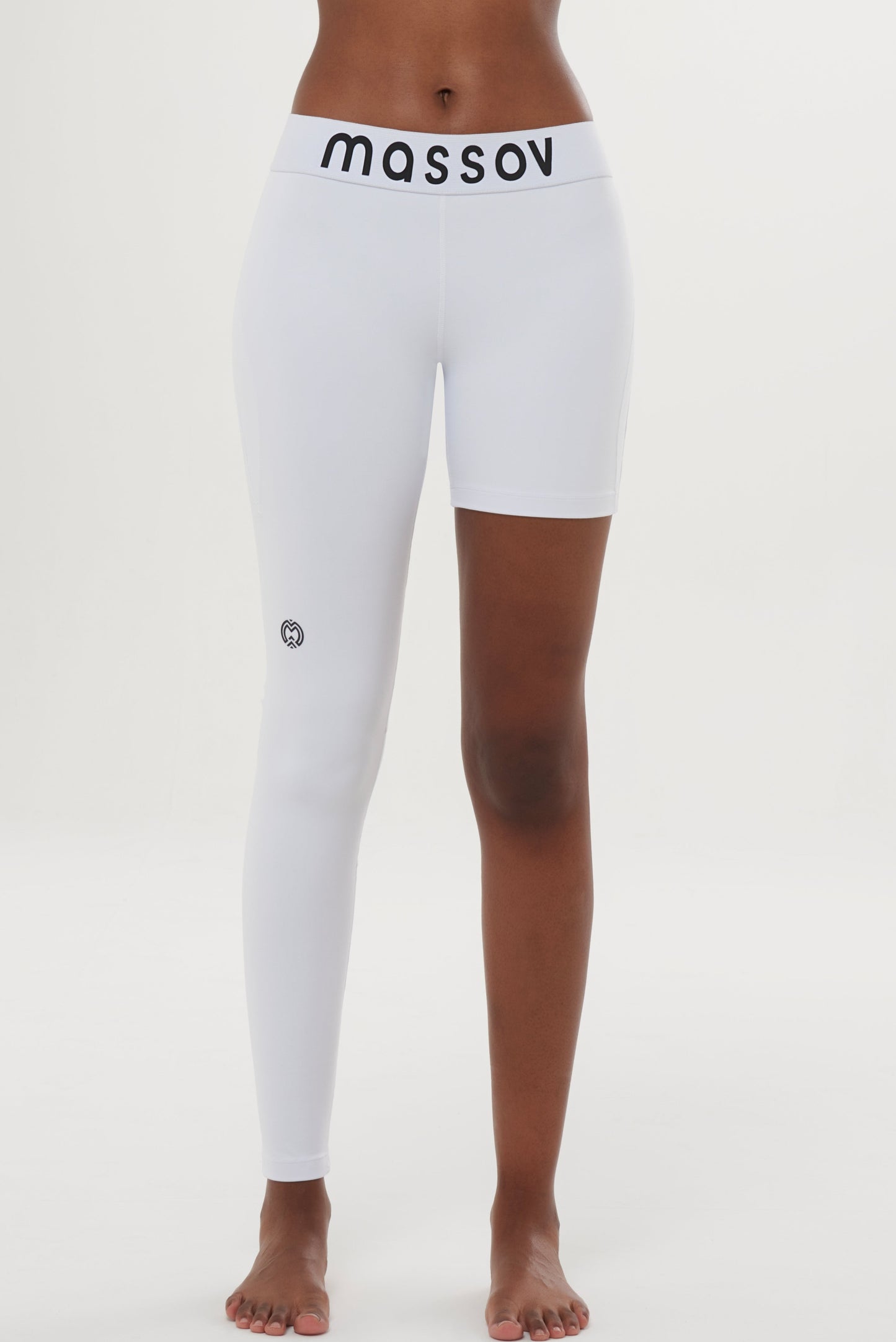 A person stands barefoot in Massov ProForm® Women's One Leg Compression Pants: the left is a full-length leg, the right a biker short, with "massov" in black on the mid-waistband against a plain white background.
