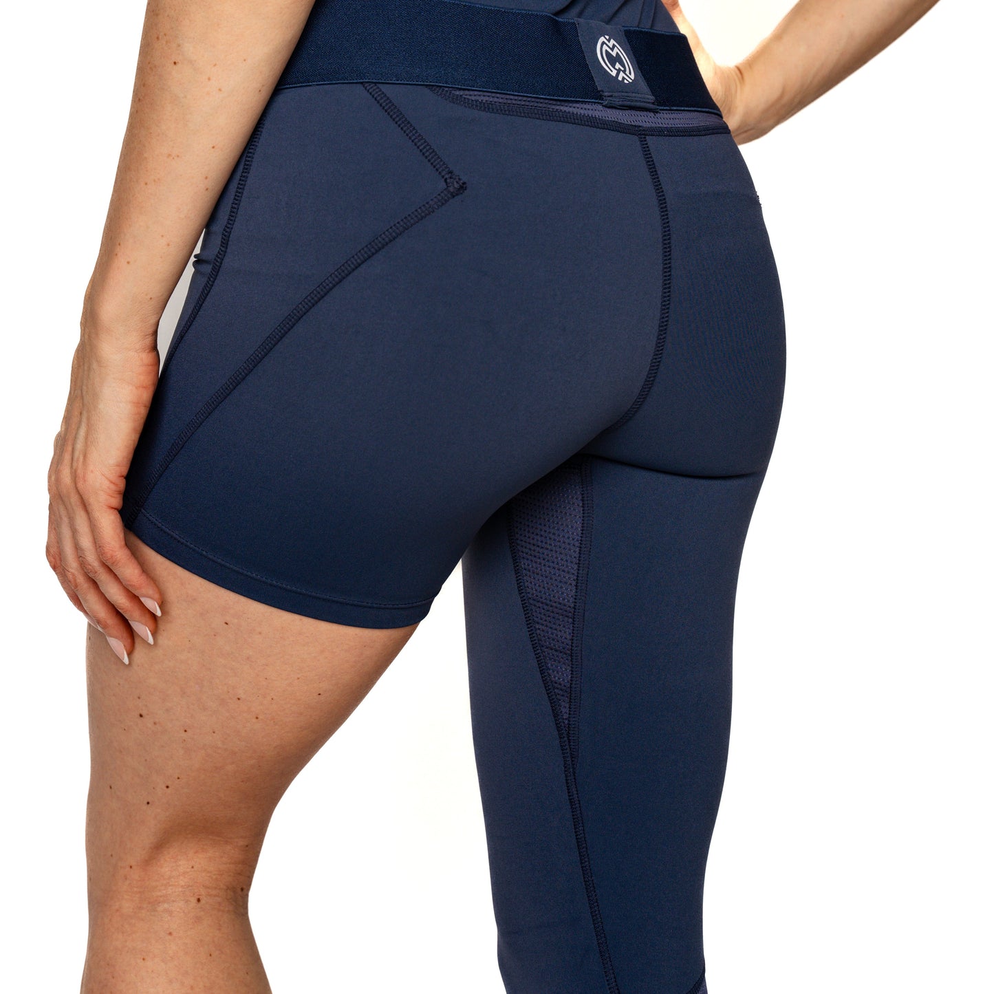 A person wearing Massov ProForm® Women’s One Leg Compression Pants in high-waisted navy, featuring side seams, a back pocket, and visible stitching, stands with one hand on their hip. Only the lower torso and upper legs are shown.