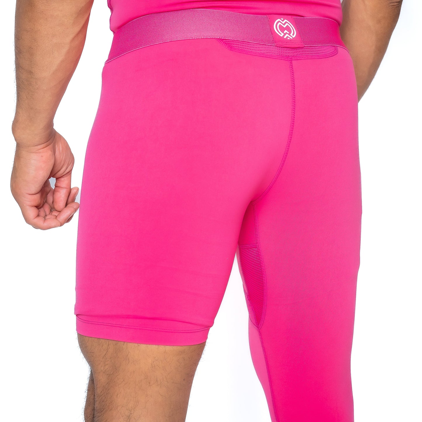 A boy is seen from the back and side wearing Massov ProForm® Youth Boys' One Leg Compression Pants. The bright pink fitted pants have a small white heart logo on the waistband. Only his lower back, hip, and upper thighs are visible.