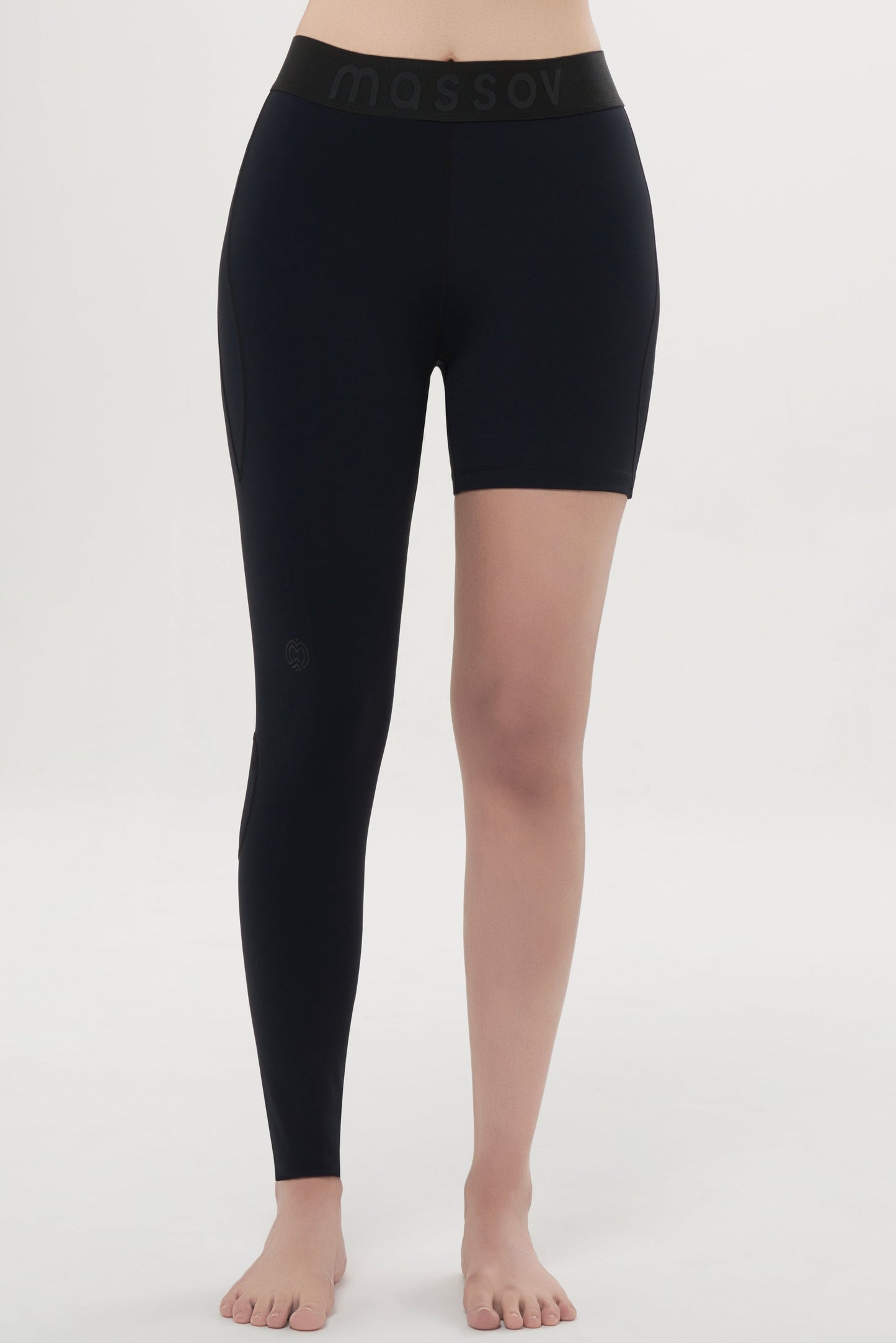 A person stands barefoot against a white background wearing Massov ProForm® Youth Girls' One Leg Compression Pants, featuring a black waistband with subtle "massov" lettering; the left leg is fully covered, the right is styled like shorts.