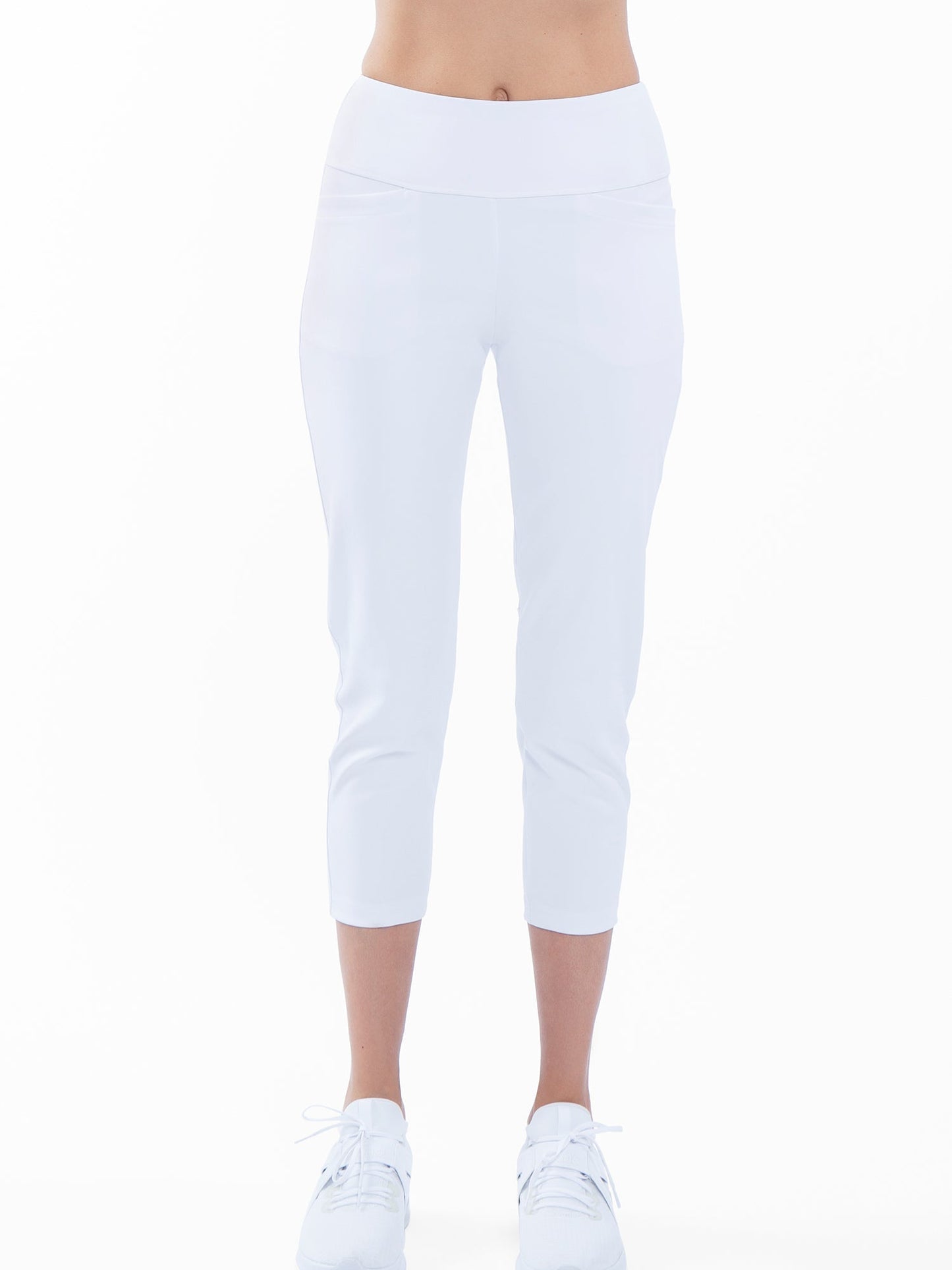 A person faces forward wearing inPhorm NYC’s Quick Dry Women's Golf 24" Capri in white with athletic shoes. The capri offers UPF 50+ protection and quick-dry fabric, shown against a plain white background that highlights the activewear.