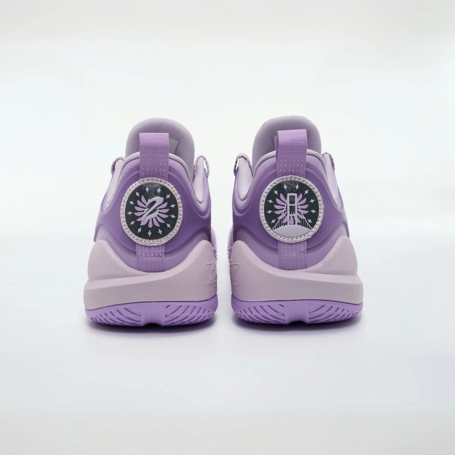 A pair of BPBazaar Rigorer BP1 “Valkyrie” sneakers in light purple, shown from the back with circular heel tabs featuring white graphic designs and star patterns, textured soles, and smooth uppers in multiple purple shades on a white background.