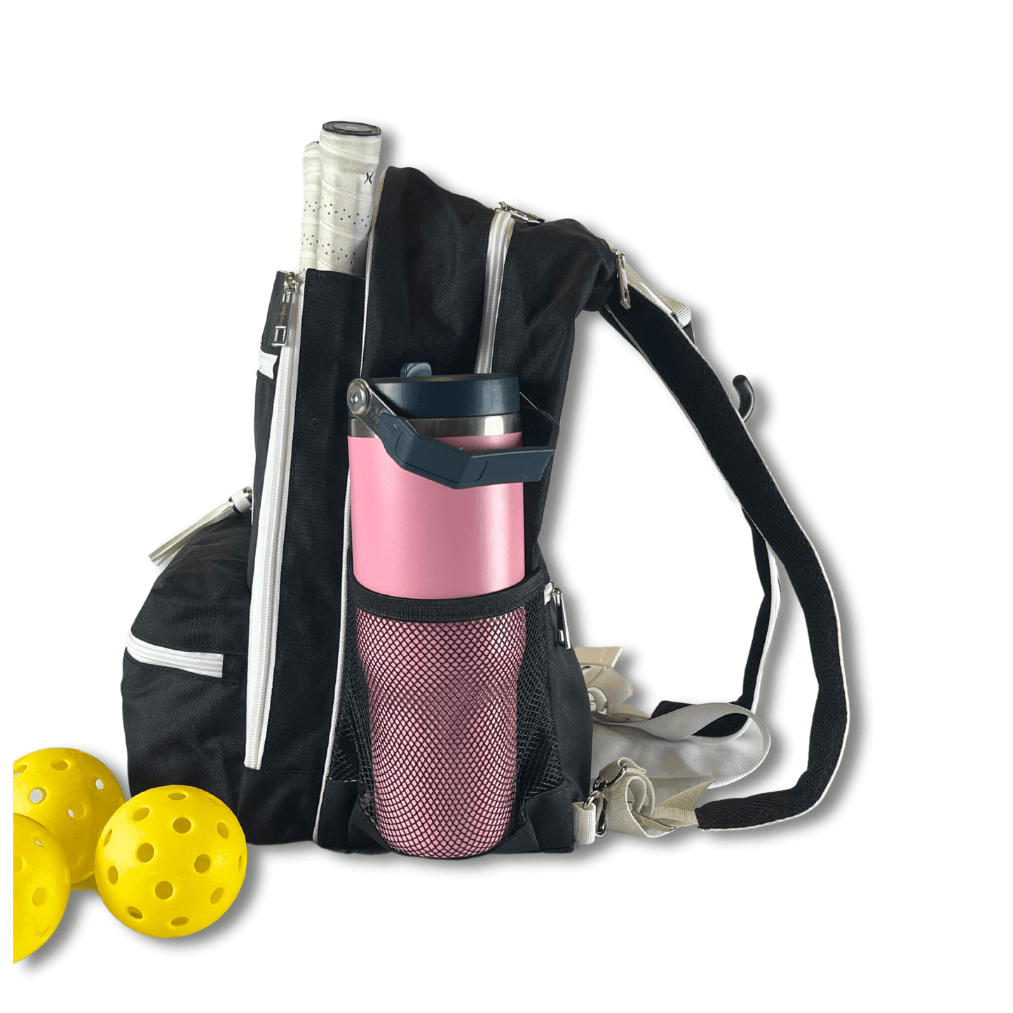 The Fresh Pickle Teddi Pickleball Backpack in black has white zippers and straps, a spacious main compartment for your tennis racket, a pink water bottle in the side mesh pocket, and comes with two yellow pickleballs on a white background.