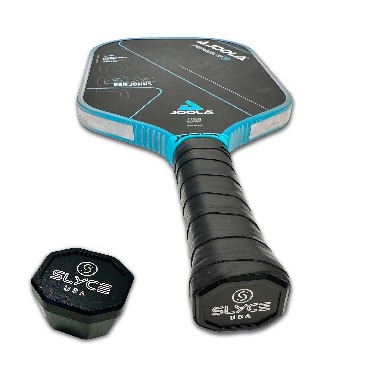 A JOOLA Ben Johns USA pickleball paddle with a black grip lies angled upward beside a black, octagonal Slyce Sport SLYCE Weighted SpeedCap (28g, 1.0 oz.) Paddle Performance Enhancer, both set against a white background.
