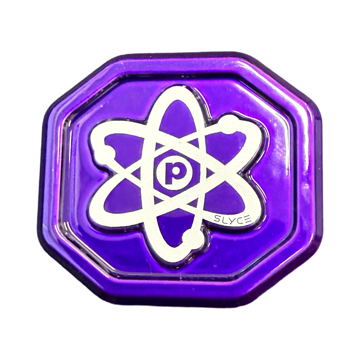 A shiny purple octagonal pin by Slyce Sport features a white atomic symbol with “p” at the center, inspired by the Special Edition SpeedCap for Proton Paddle Performance Enhancer. “SLYCE” is beside the design, and the pin has a 3D metallic look.